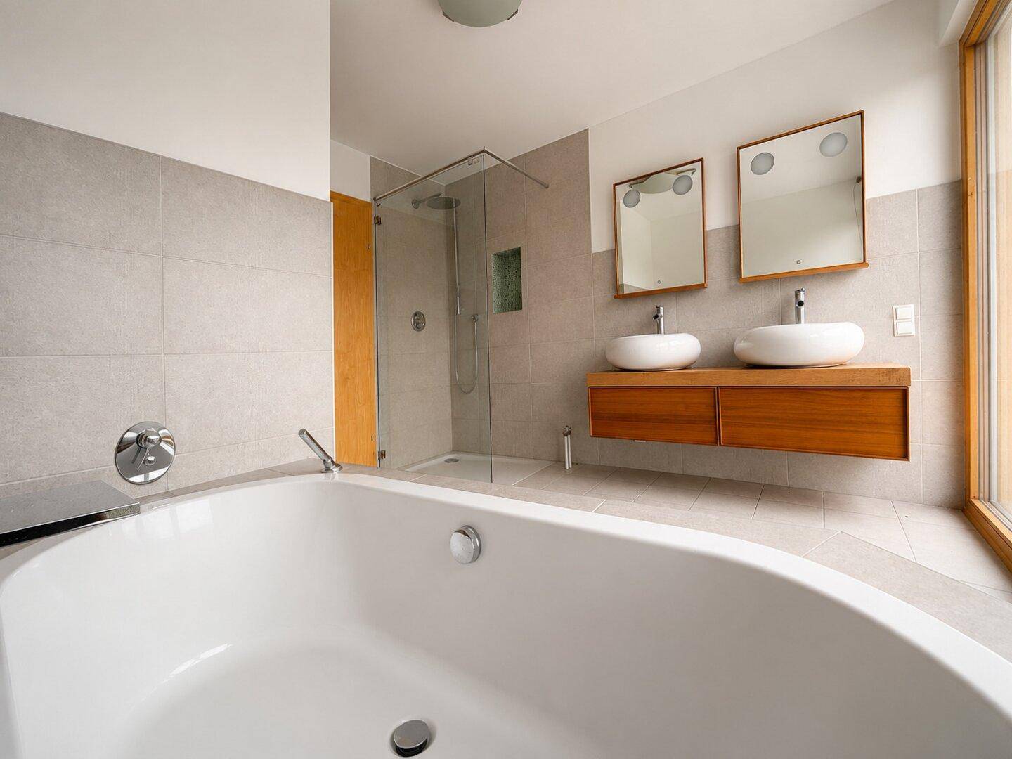 Modernes Badezimmer mit Eckbadewanne, begehbarer Dusche, Doppelwaschbecken und großem Fenster.