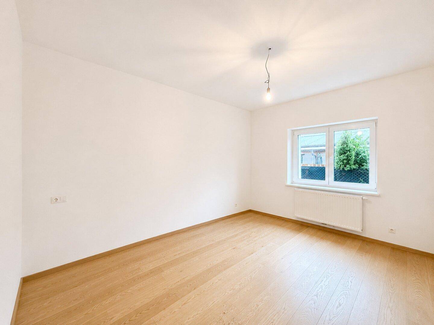 Leeres Zimmer mit Holzboden und weißen Wänden, ideal als Schlafzimmer oder Arbeitszimmer nutzbar.