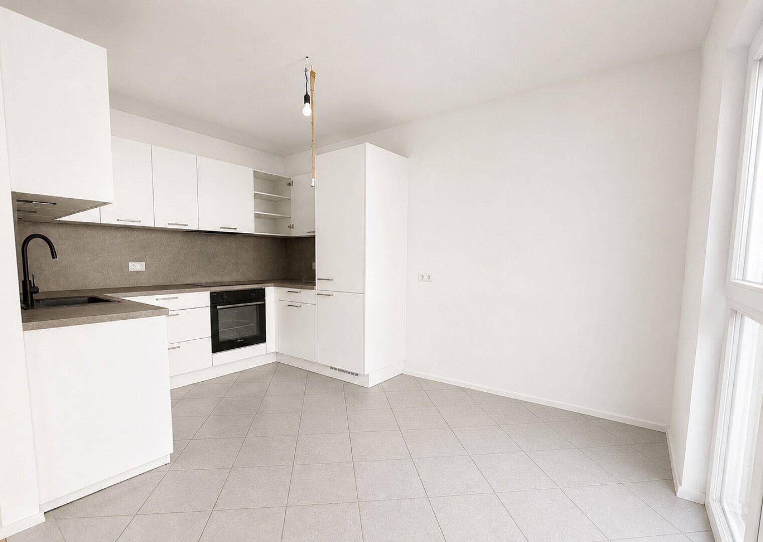 Moderne Küche mit weißen Schränken, integriertem Backofen und Fliesenboden.