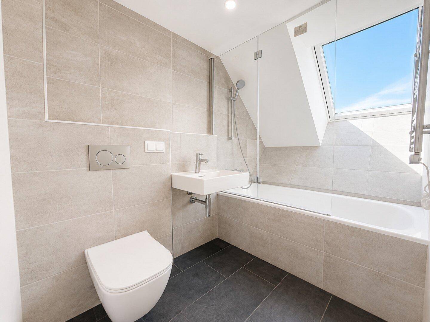 Modernes Badezimmer mit Badewanne, Wand-WC, Waschbecken und Dachfenster.