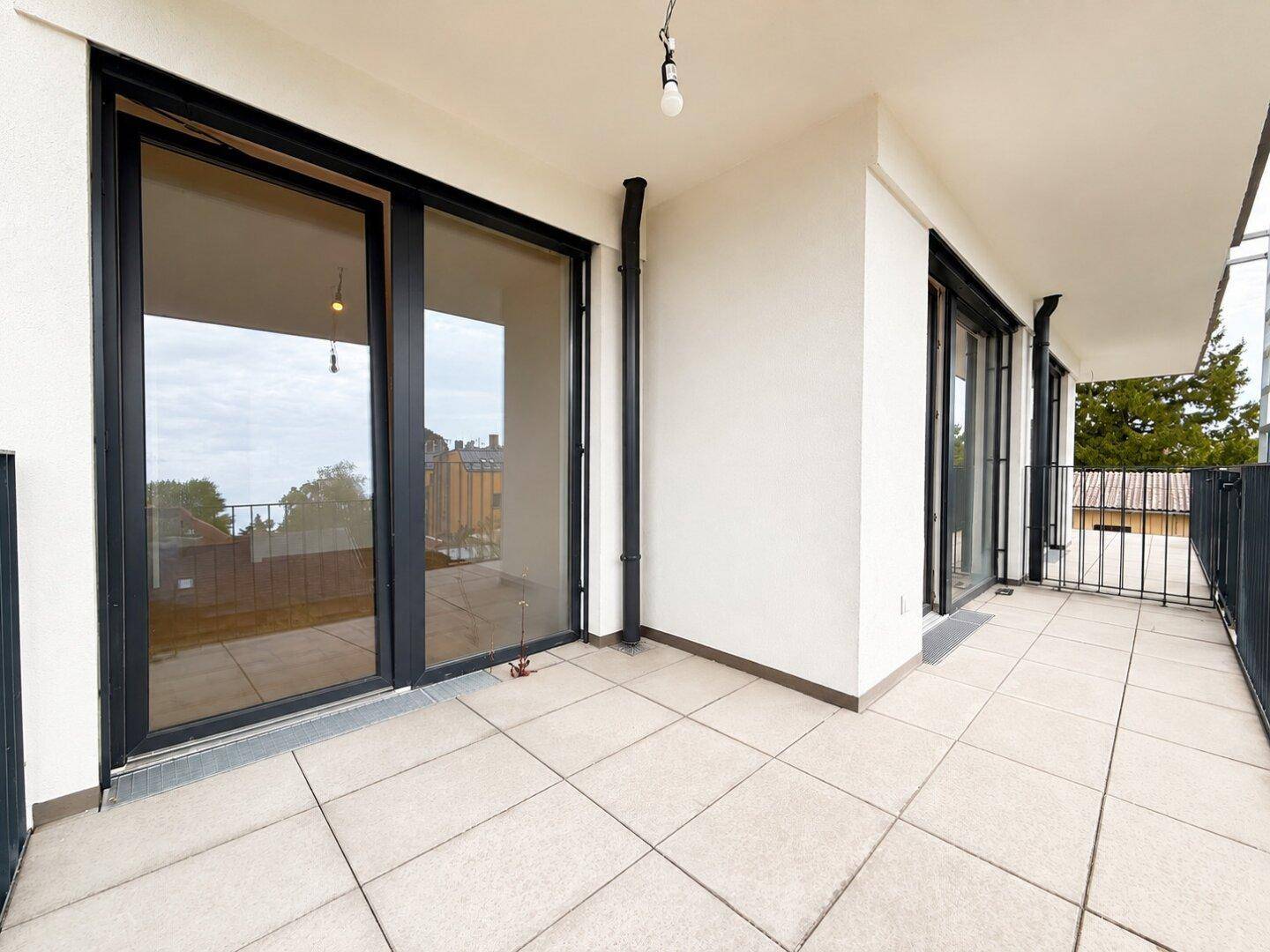 Geräumiger Balkon mit Fliesenboden und schwarzem Geländer, ideal für entspannte Stunden im Freien.
