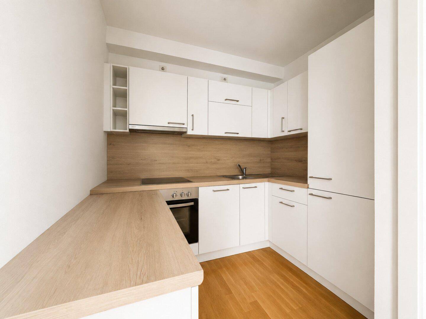 Kompakte, moderne Küche mit weißen Schränken, Holz-Arbeitsplatten und integrierten Geräten.