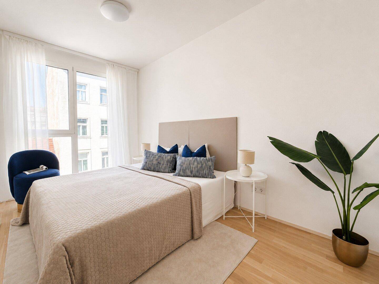 Gemütliches Schlafzimmer mit Doppelbett, modernem Sessel und großem Fenster.