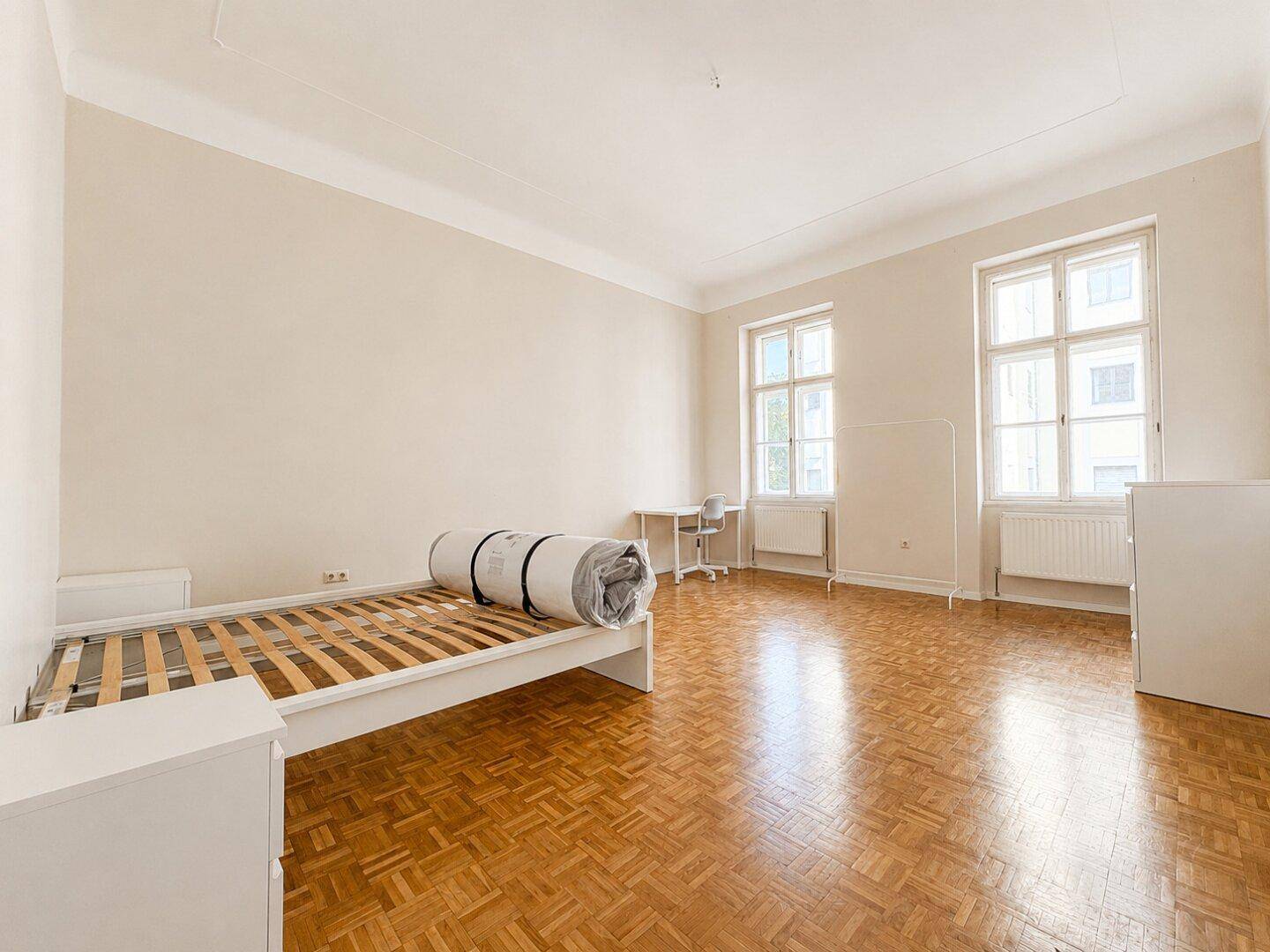 Geräumiges Schlafzimmer mit Parkettboden und großen Fenstern, bereit zur individuellen Einrichtung.
