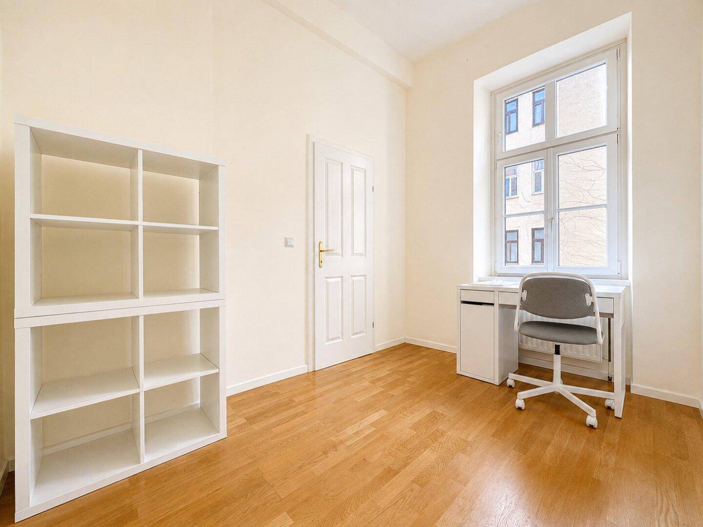 Helles Arbeitszimmer mit Parkettboden, weißem Regal und Schreibtisch, ideal für Home-Office.