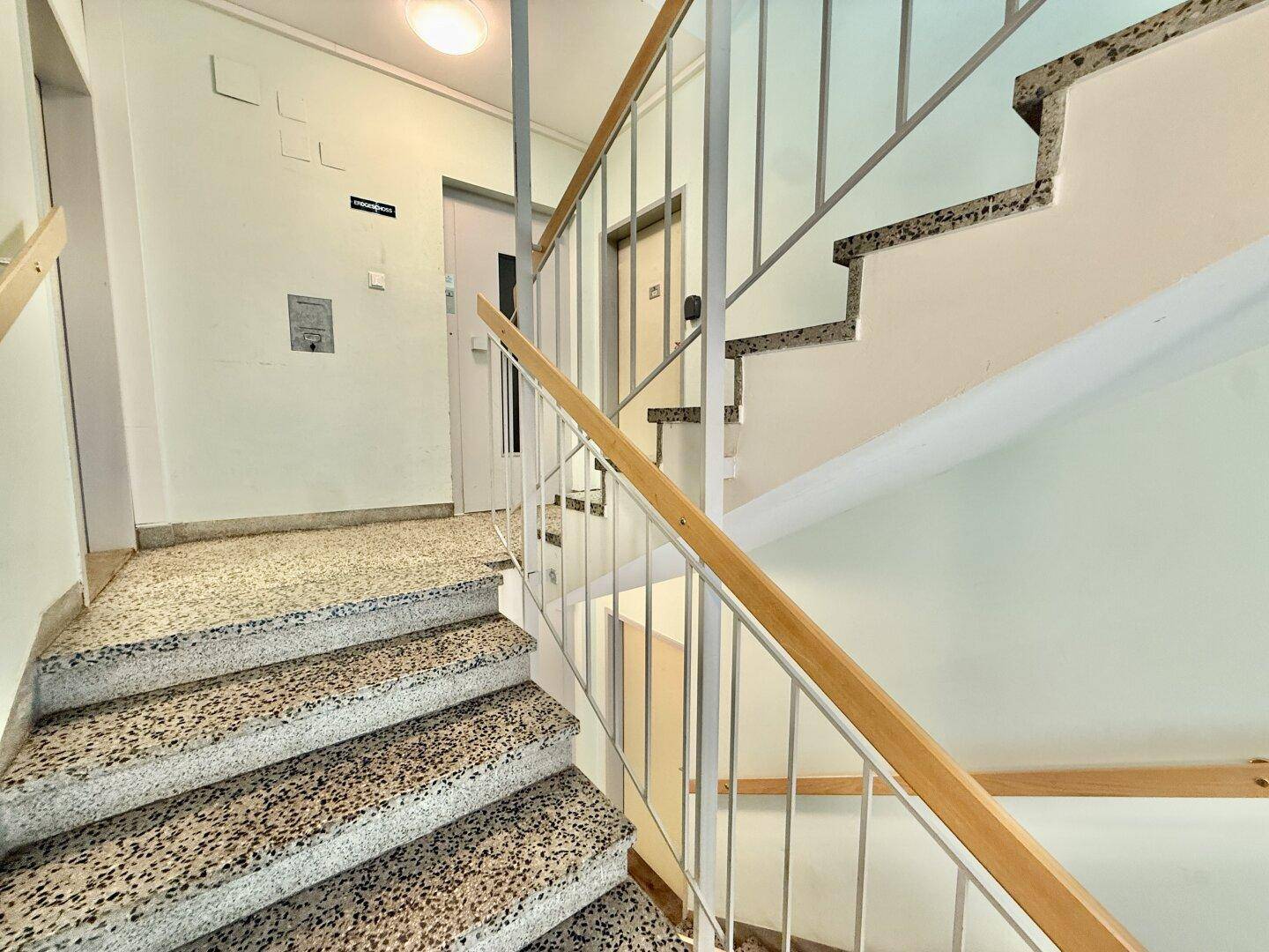 Treppenhaus mit Terrazzostufen und Metallgeländer in einem Mehrfamilienhaus, das die verschiedenen Etagen verbindet.