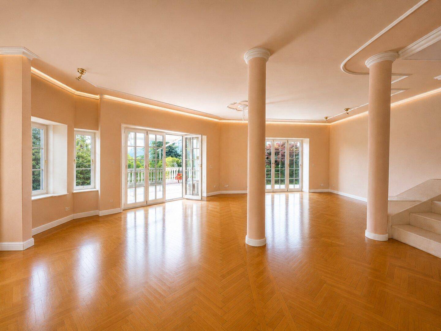 Geräumiges, leeres Wohnzimmer mit Fischgrätparkett, hohen Decken und Zugang zur Terrasse.