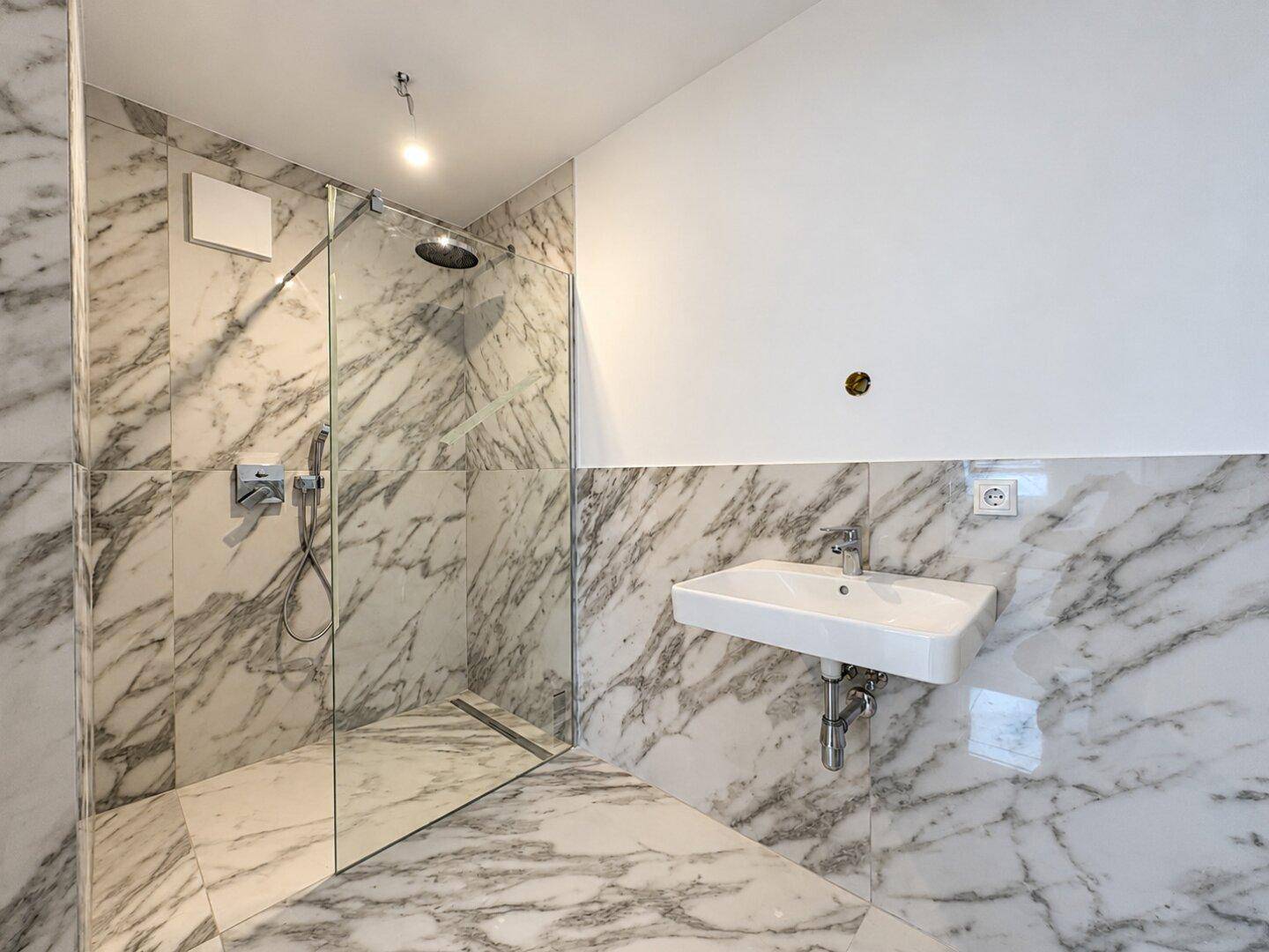 Modernes Badezimmer mit Marmorfliesen, ebenerdiger Dusche und Einzelwaschbecken.