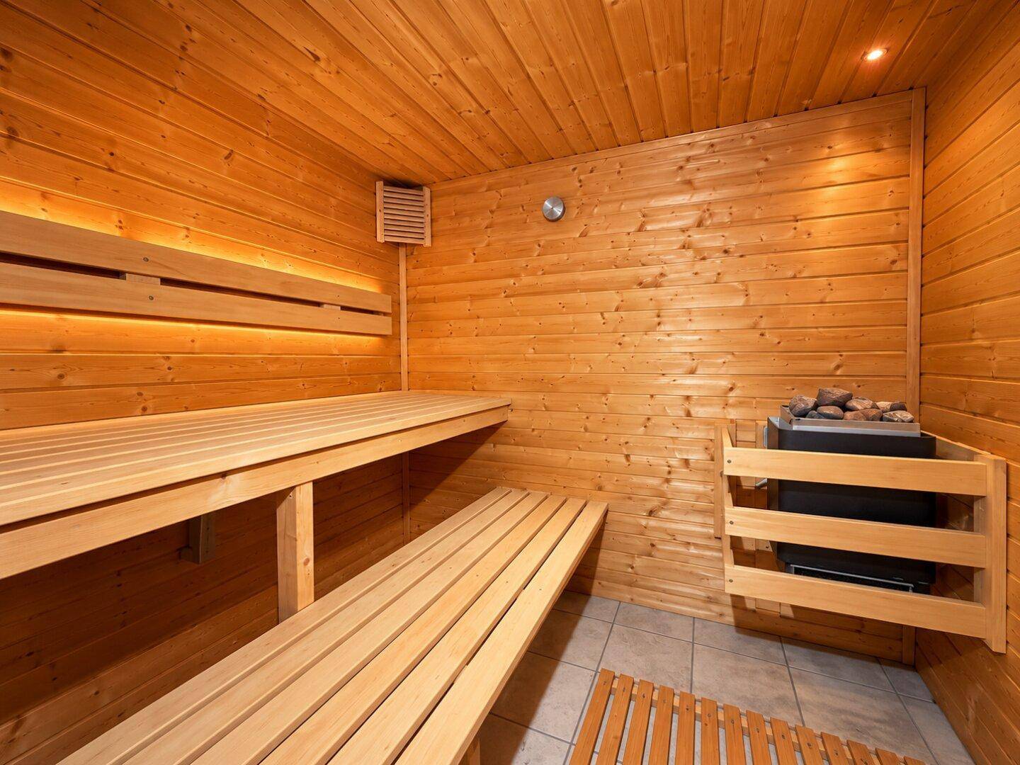 Private Sauna mit Holzbänken und Saunaofen, ideal zur Entspannung.