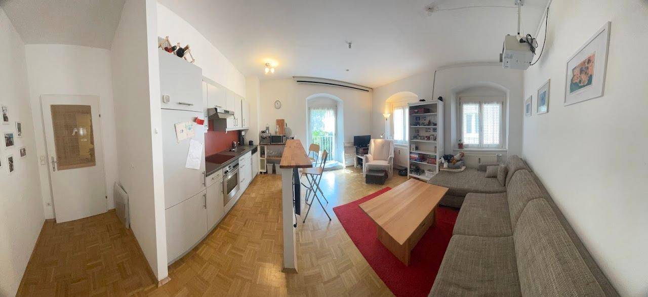 Weitläufiger Wohn- und Essbereich mit offener Küche, Sofa und viel Tageslicht.