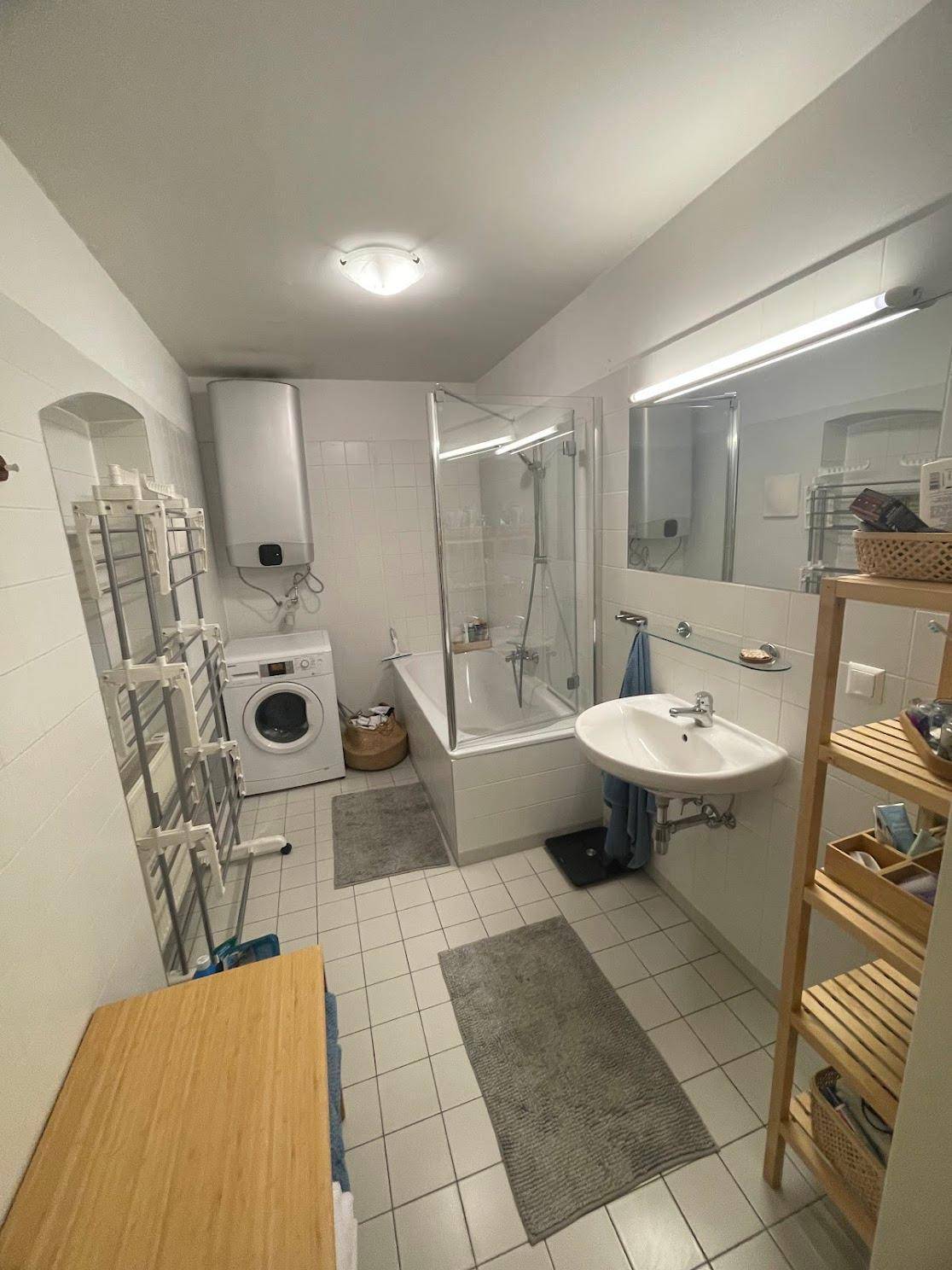 Funktionales Badezimmer mit Badewanne, Duschabtrennung, Waschbecken und Waschmaschine.