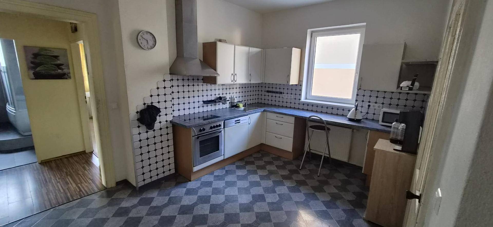 Funktionale Küche mit kariertem Fliesenboden, Fenster und Einbaugeräten.