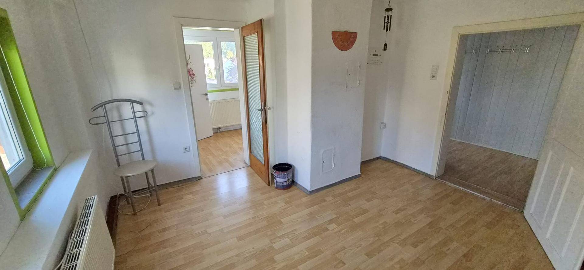 Heller Flur mit Holzfußboden und Zugang zu mehreren Zimmern, bietet vielseitige Nutzungsmöglichkeiten.