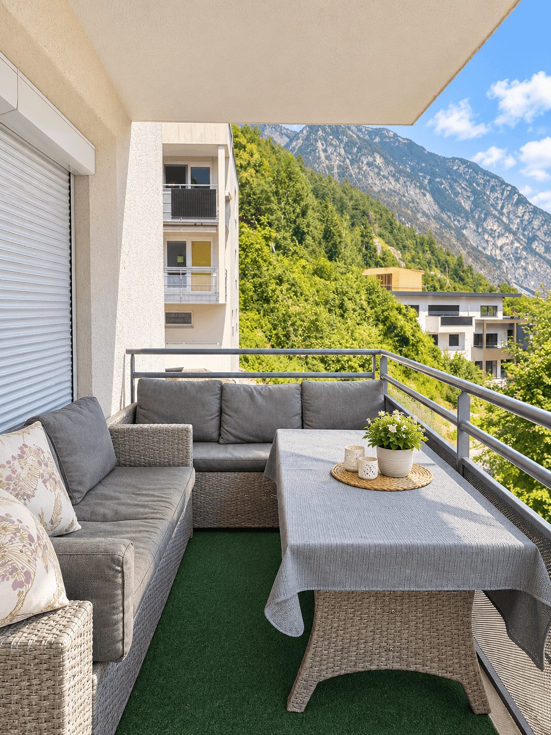 Möblierter Balkon mit Rattan-Sitzgruppe und beeindruckendem Bergblick in die Natur.