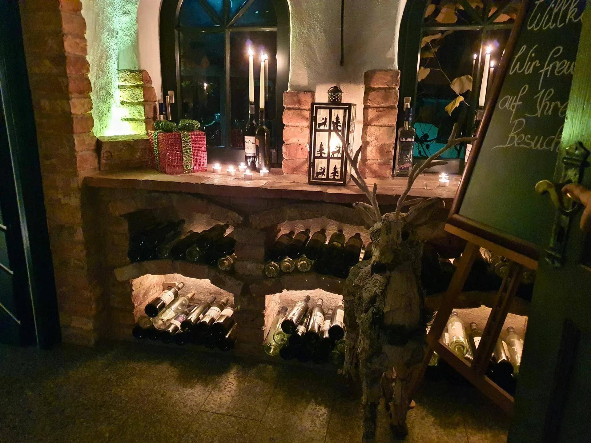 Rustikaler Weinkeller mit Flaschen in Nischen, Kerzenlicht und traditioneller Dekoration.
