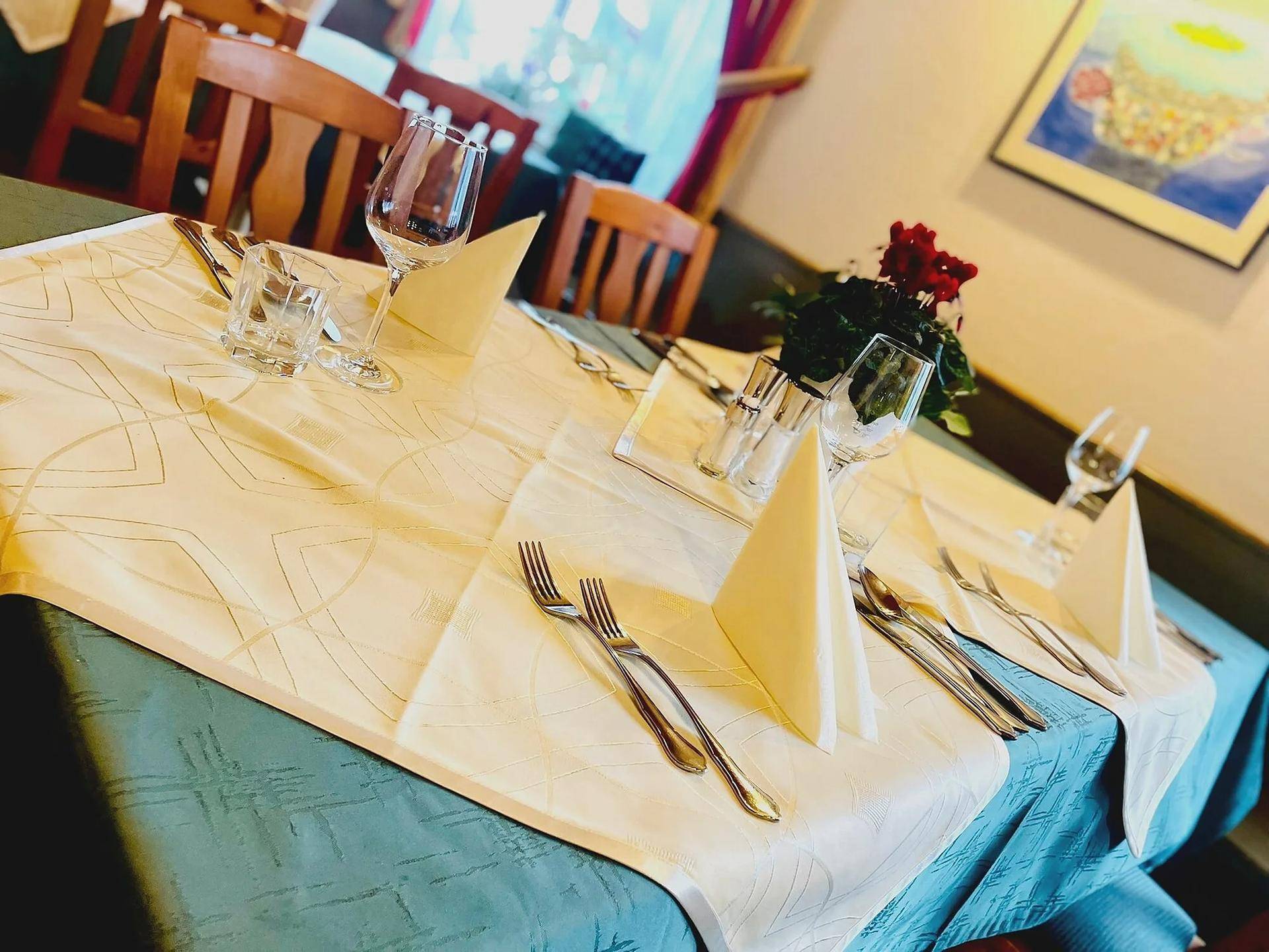 Festlich gedeckter Esstisch in einem Restaurant mit elegantem Geschirr und Blumendekoration.