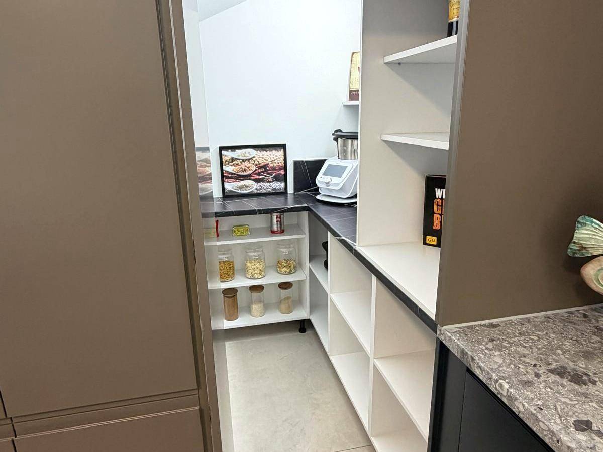 Gut organisierte Speisekammer mit Regalen und Arbeitsfläche, ideal für Küchengeräte und Vorräte.
