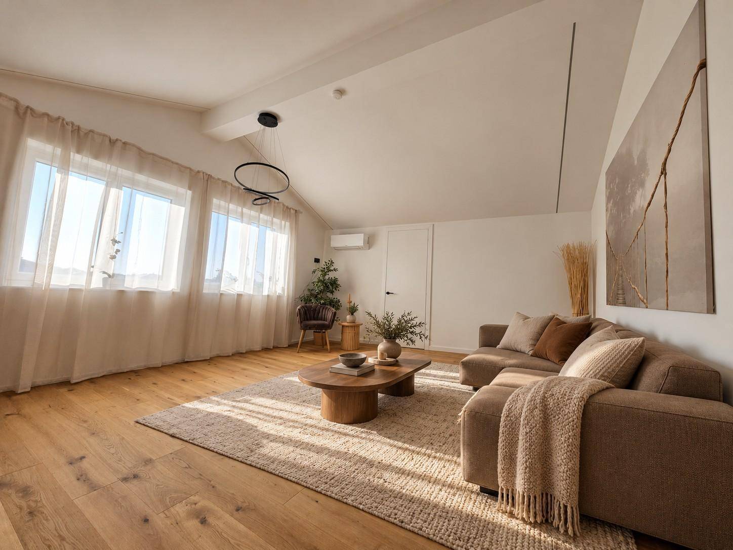 Helles Wohnzimmer im Dachgeschoss mit Holzboden, gemütlichem Sofa und Dachschräge.