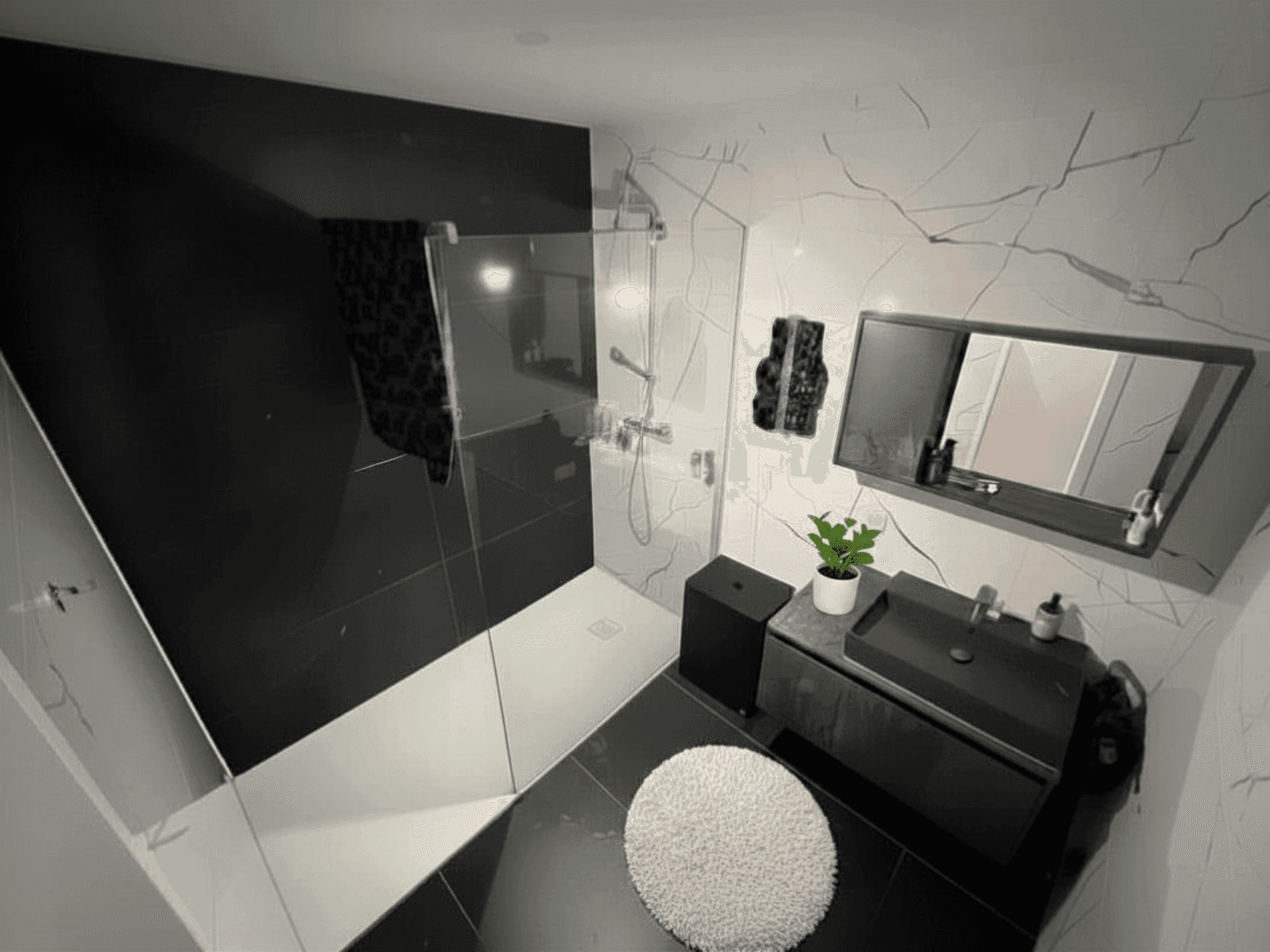 Modernes Badezimmer mit eleganten schwarz-weißen Marmorfliesen, begehbarer Dusche und stilvollem Waschtisch.