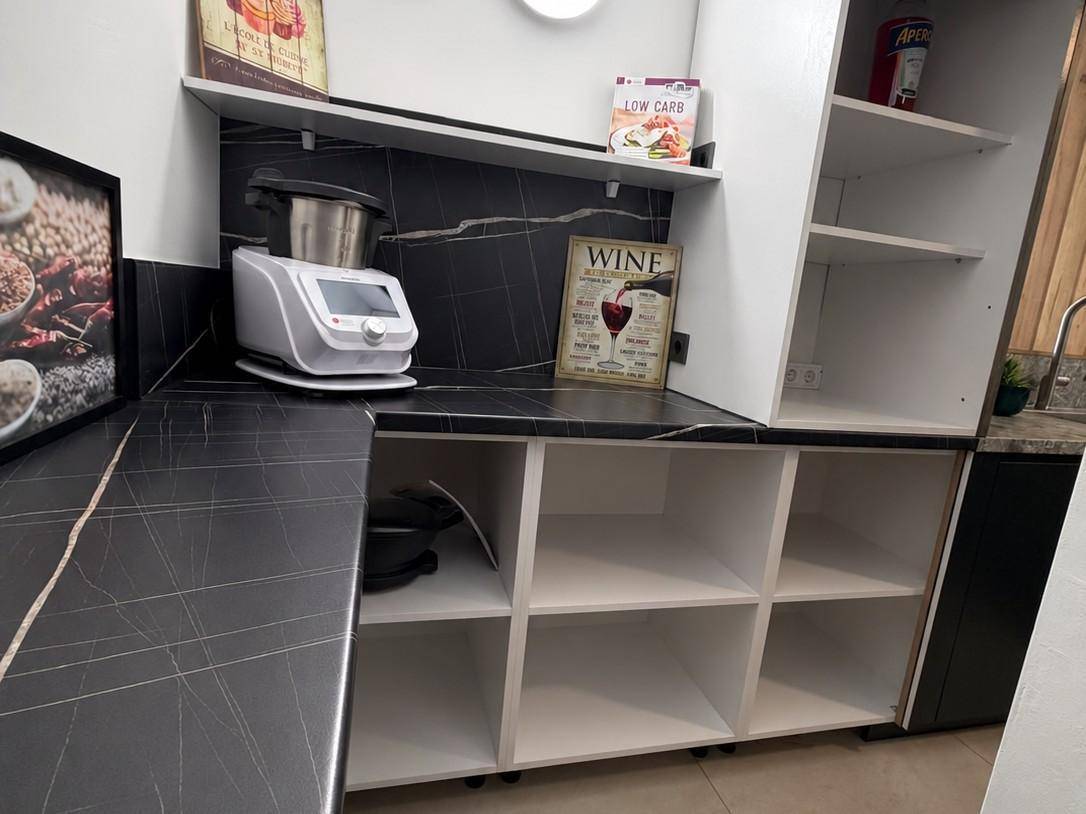 Detailansicht der Speisekammer mit schwarzer Arbeitsplatte, offenen Regalen und Küchengeräten.