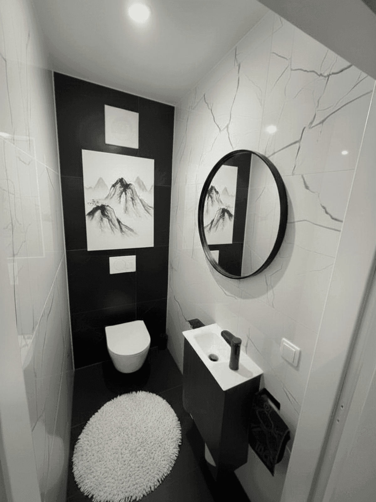Stilvolles Gäste-WC mit schwarz-weißen Marmorfliesen, wandhängender Toilette und modernem Waschbecken.