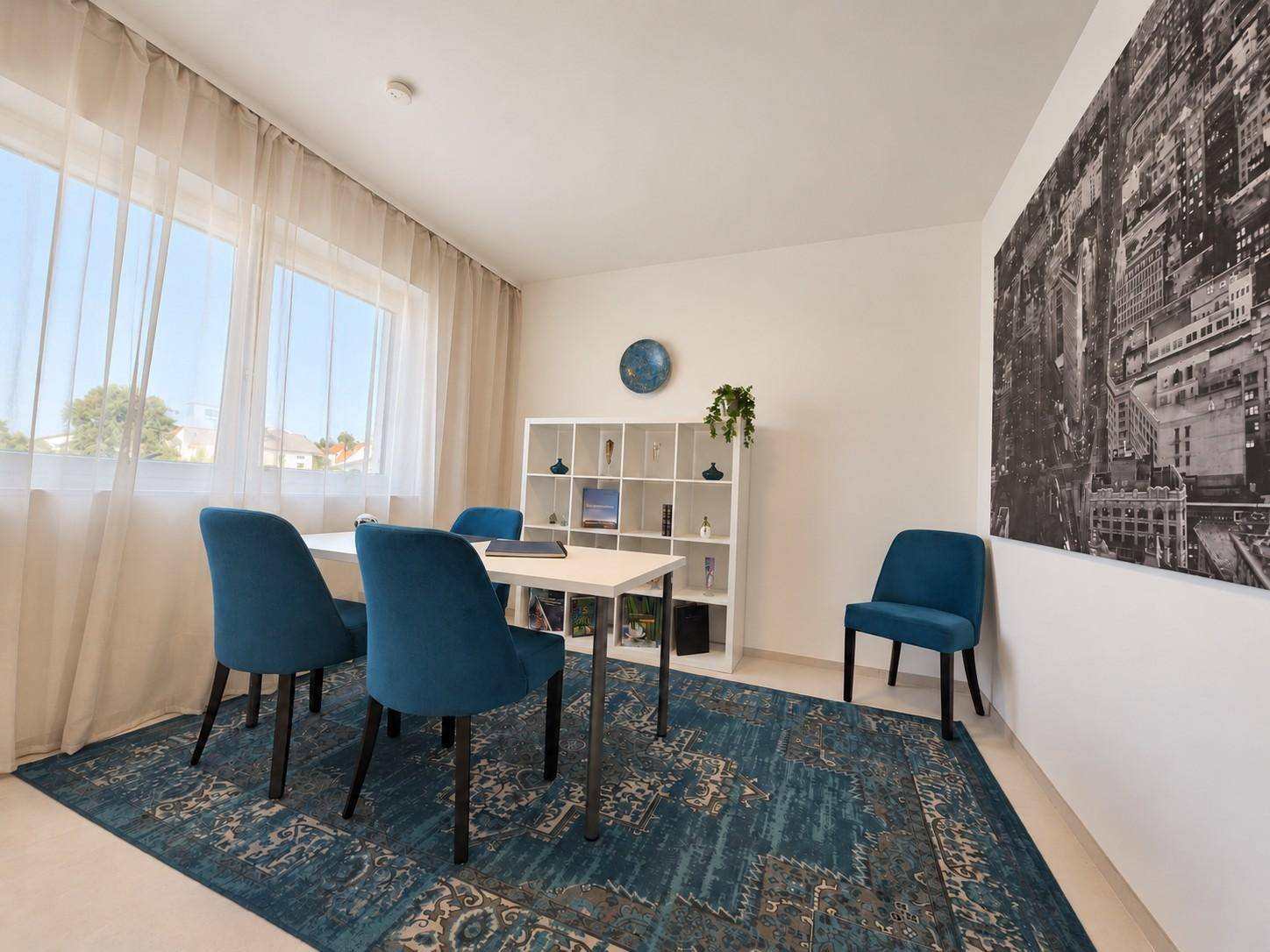 Helles Büro oder Gästezimmer mit großem Fenster, blauem Teppich und modernem Regal.