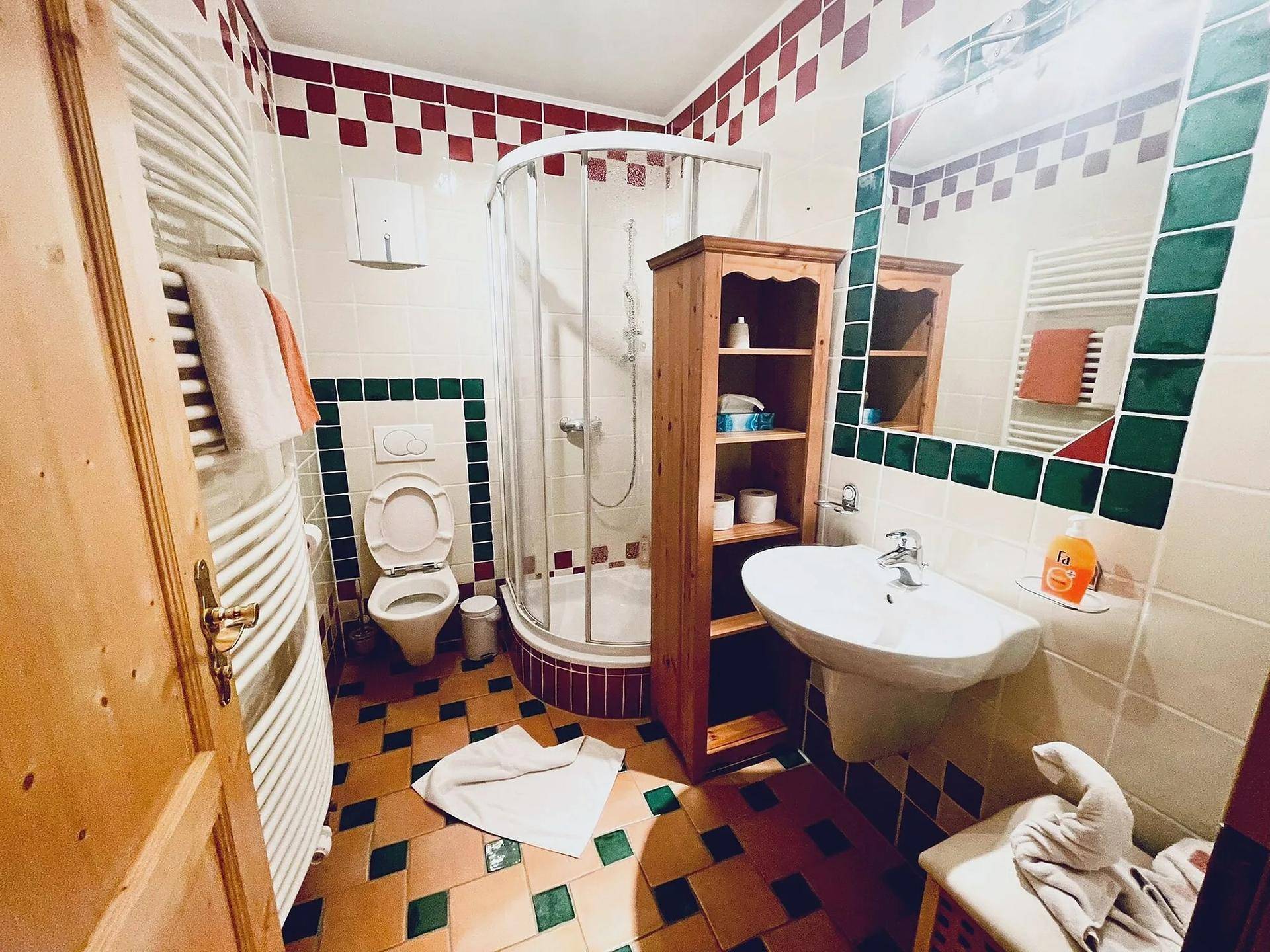 Badezimmer mit Duschkabine, Toilette, Waschbecken und beheiztem Handtuchhalter in traditionellem Design.
