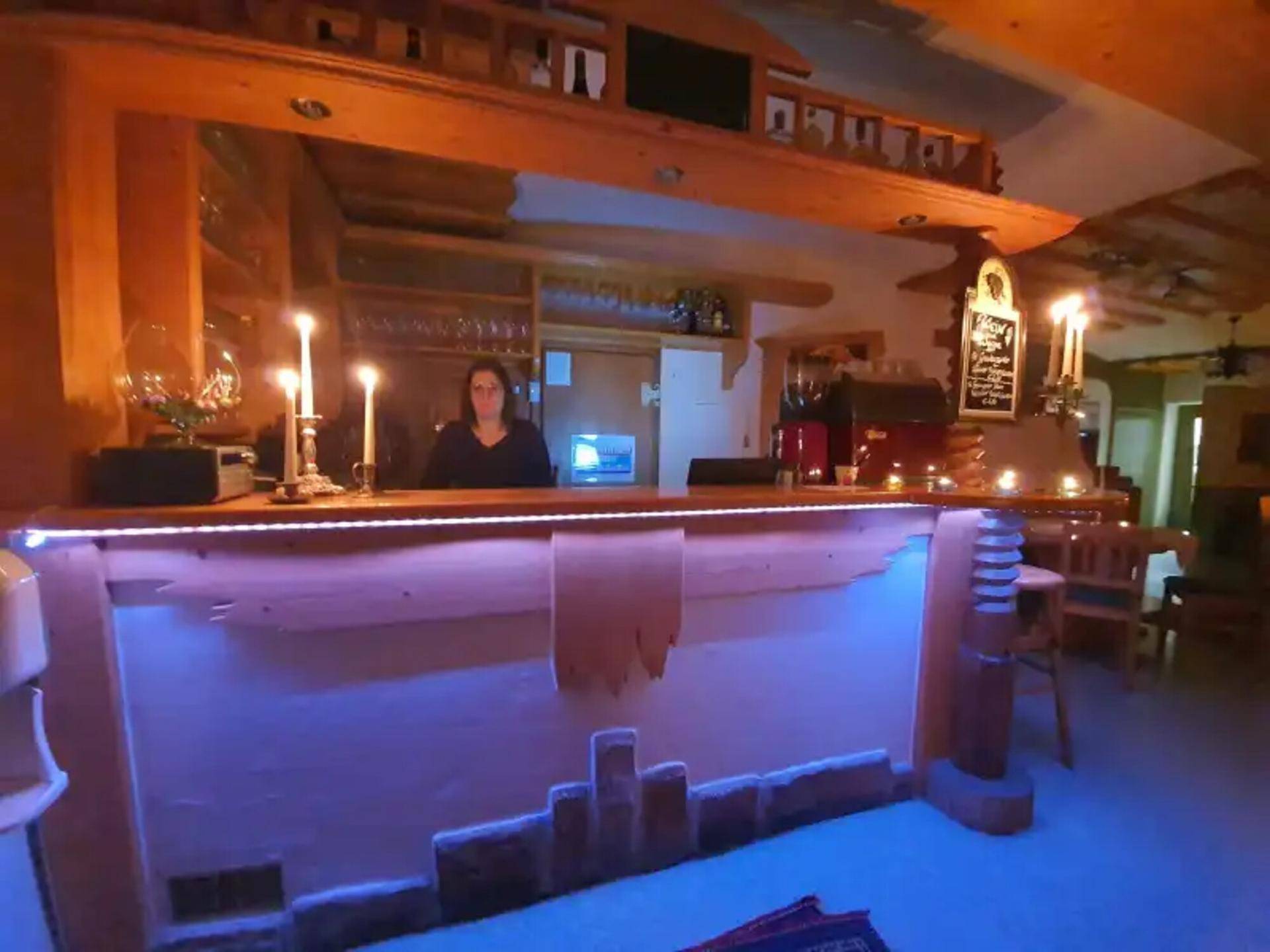 Beleuchteter Barbereich mit Holztheke und Kerzenlicht, bereit für Gäste.