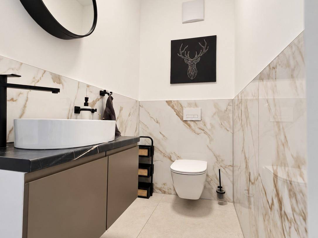 Modernes Gäste-WC mit Marmorfliesen, Aufsatzwaschbecken und wandhängender Toilette.