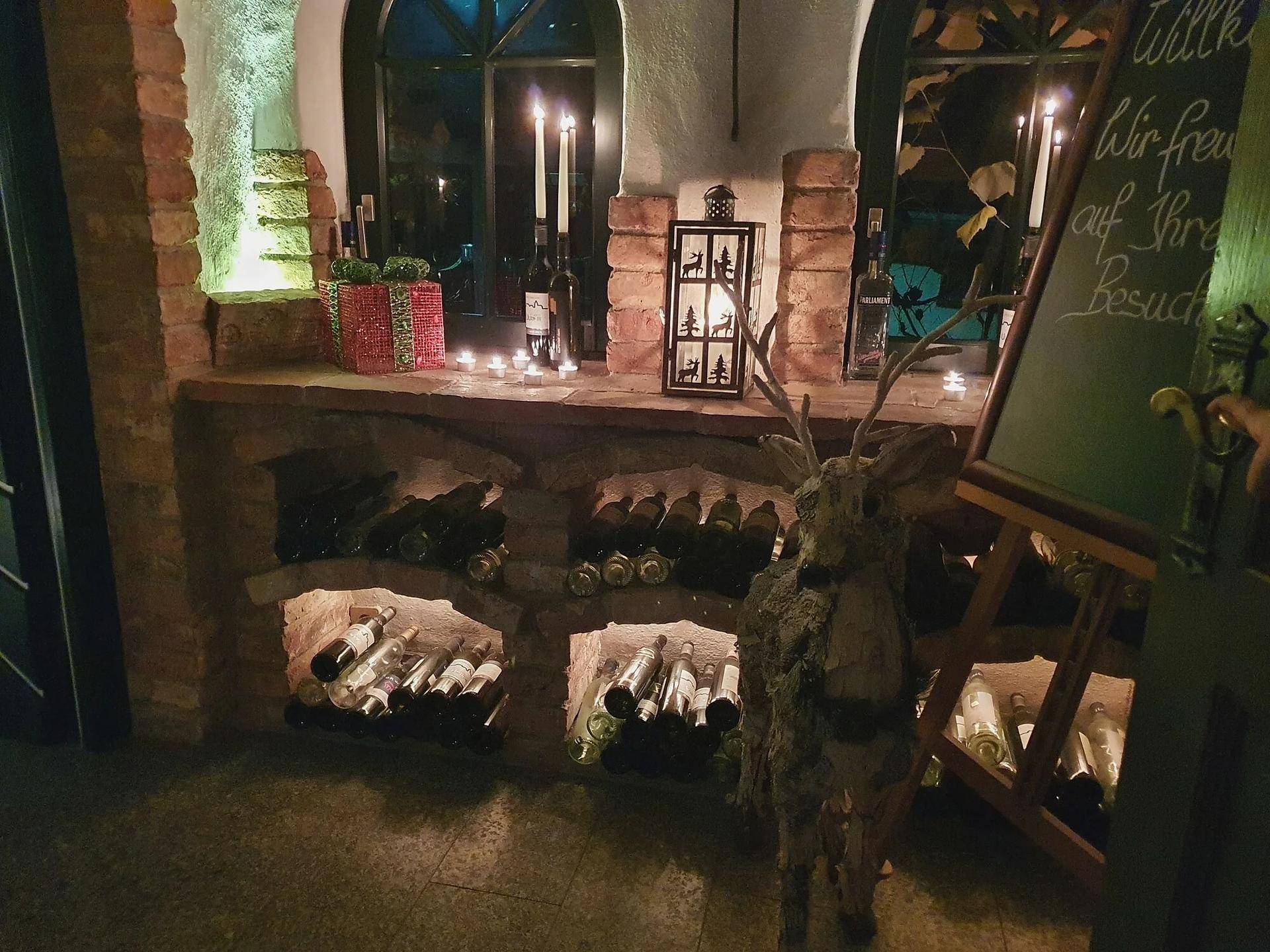 Rustikaler Weinkeller mit Flaschen in Nischen, Kerzenlicht und traditioneller Dekoration.