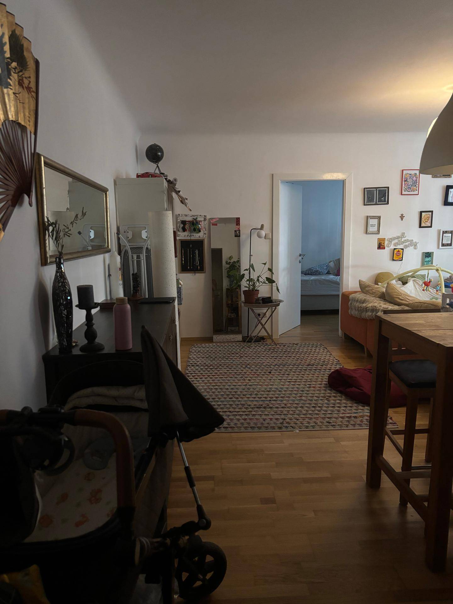 Offener Wohn- und Essbereich mit Holztisch, Teppich und Blick in ein weiteres Zimmer.