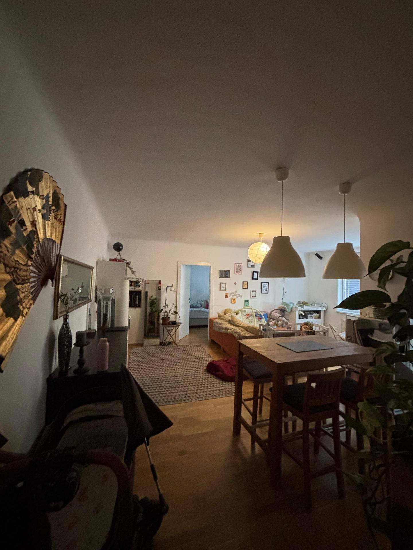 Offener Wohn-Essbereich mit Holzboden, Teppich und Blick in ein angrenzendes Zimmer.