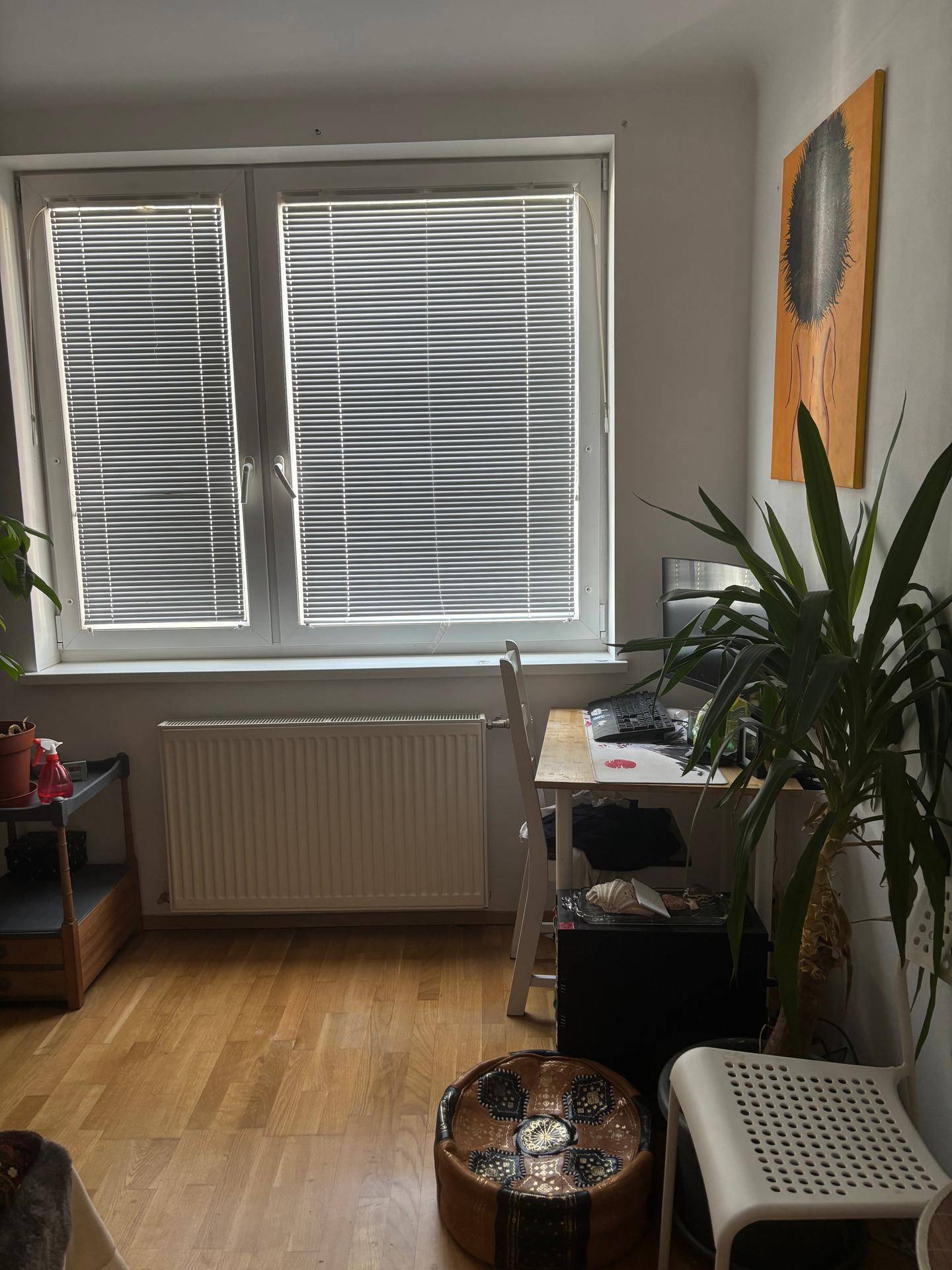 Arbeitsbereich mit Schreibtisch am Fenster, Heizkörper und hellem Holzfußboden.