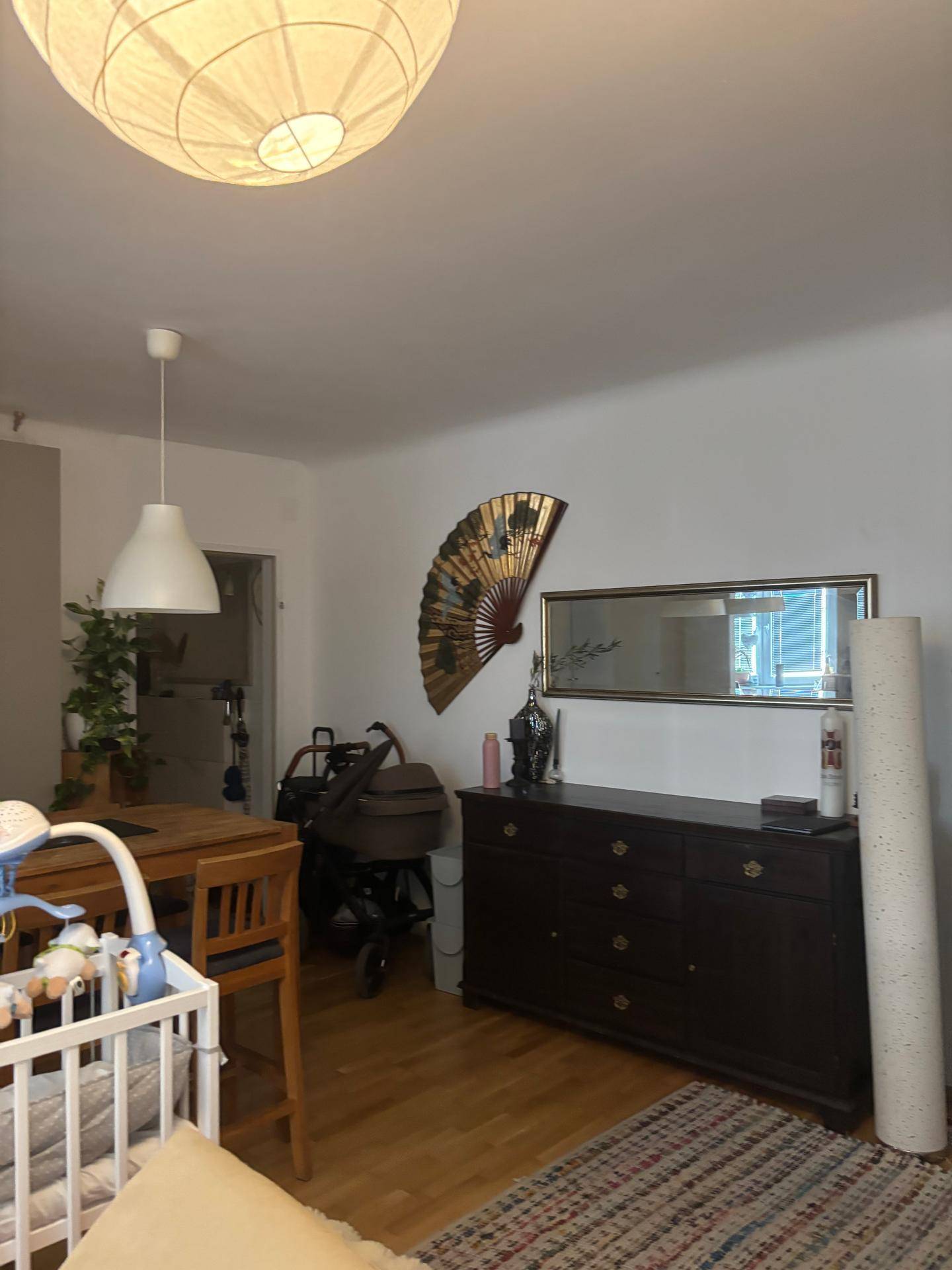 Essbereich mit dunklem Sideboard, großem Fächer an der Wand und Holztisch.