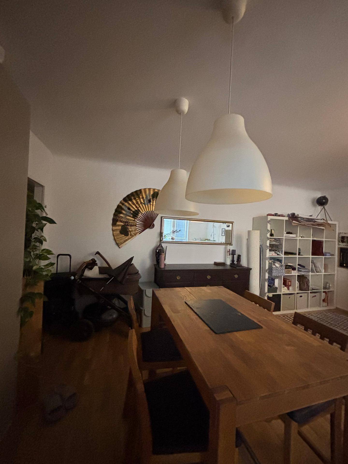 Essbereich mit Holztisch, dunklem Sideboard und dekorativem Fächer an der Wand.