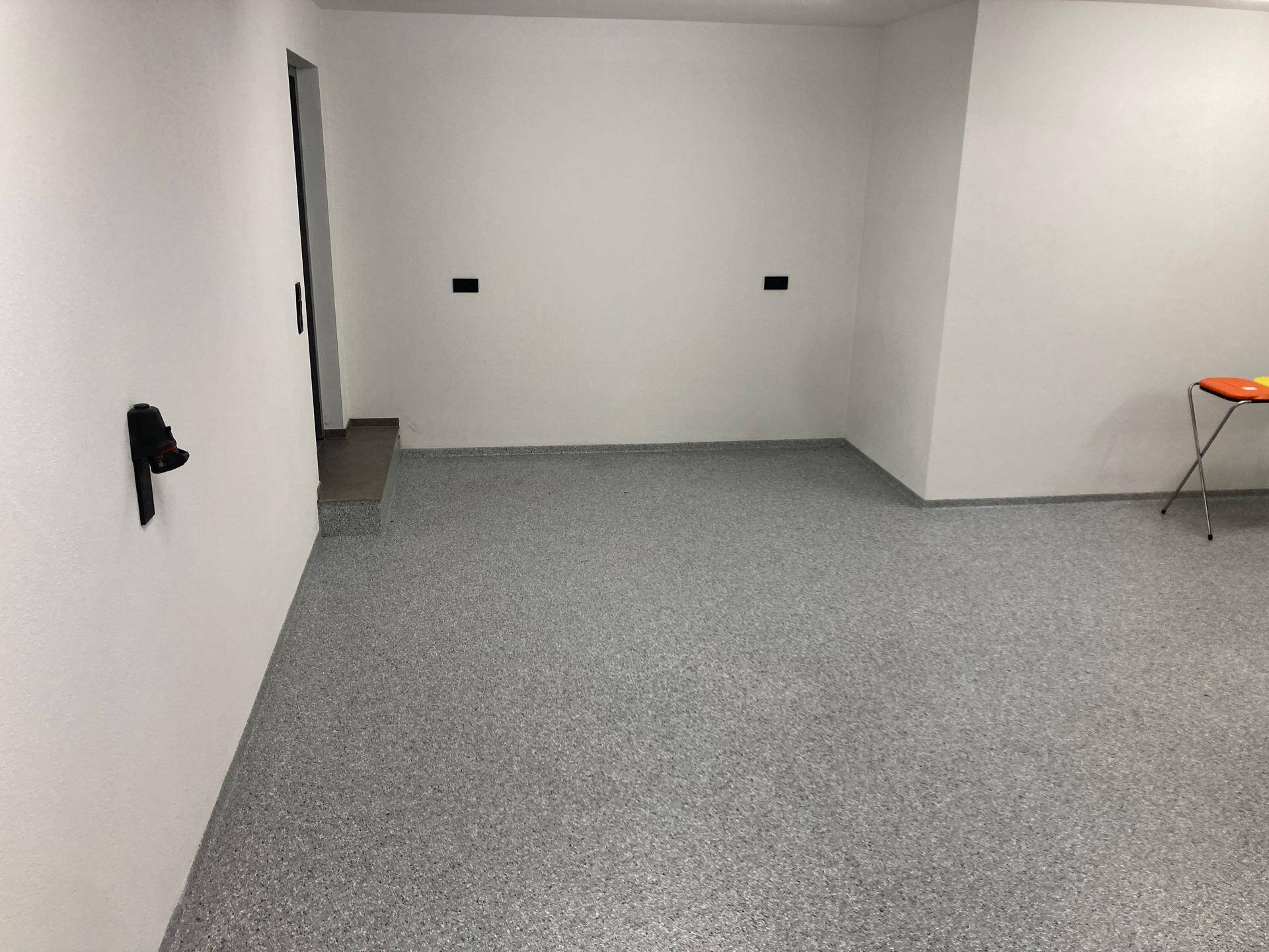 Geräumige Garage mit grauem Boden und weißen Wänden, bereit zur Nutzung.