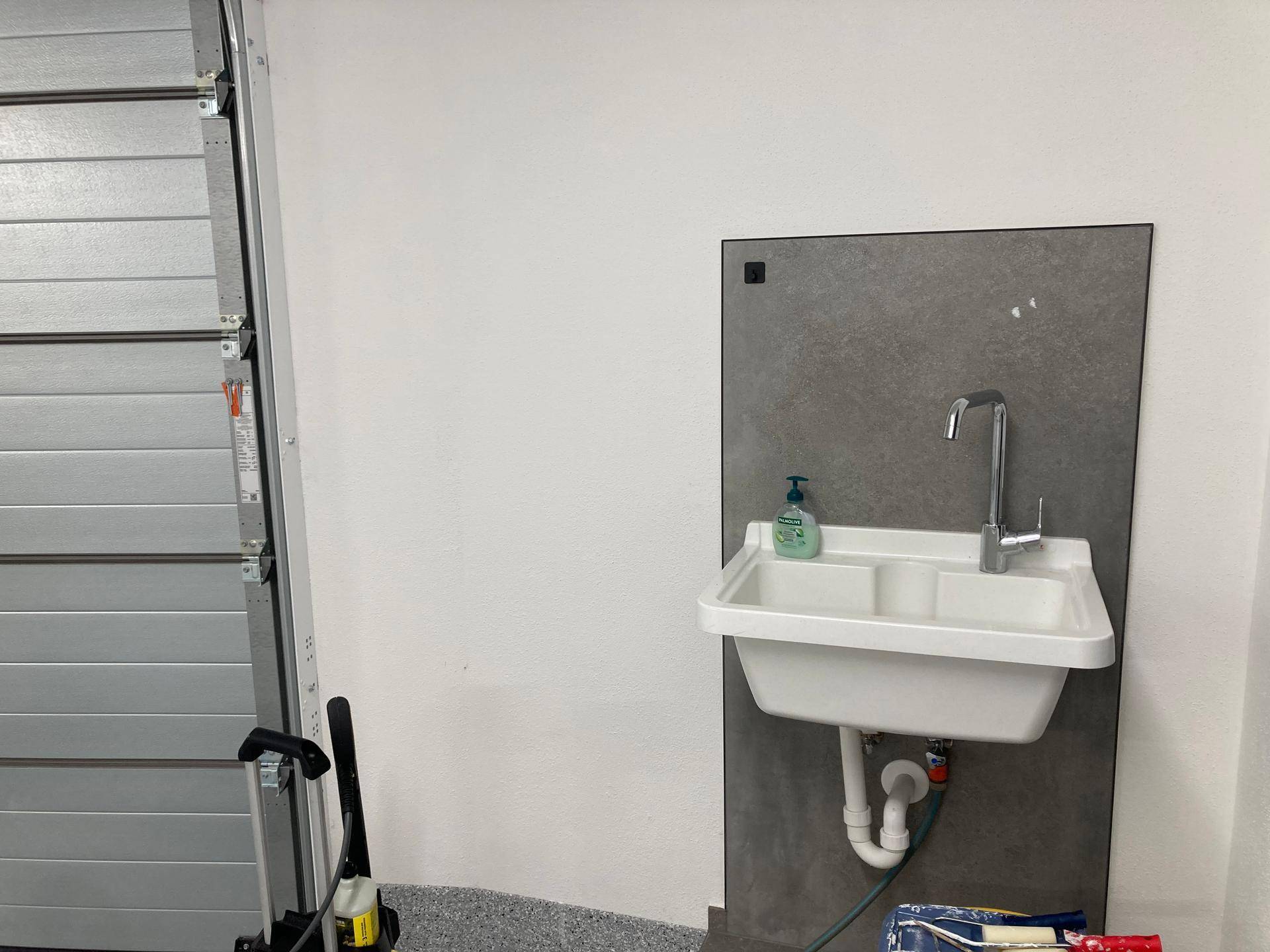 Garage mit praktischem Waschbecken und Rolltor, ideal für Reinigungsarbeiten.