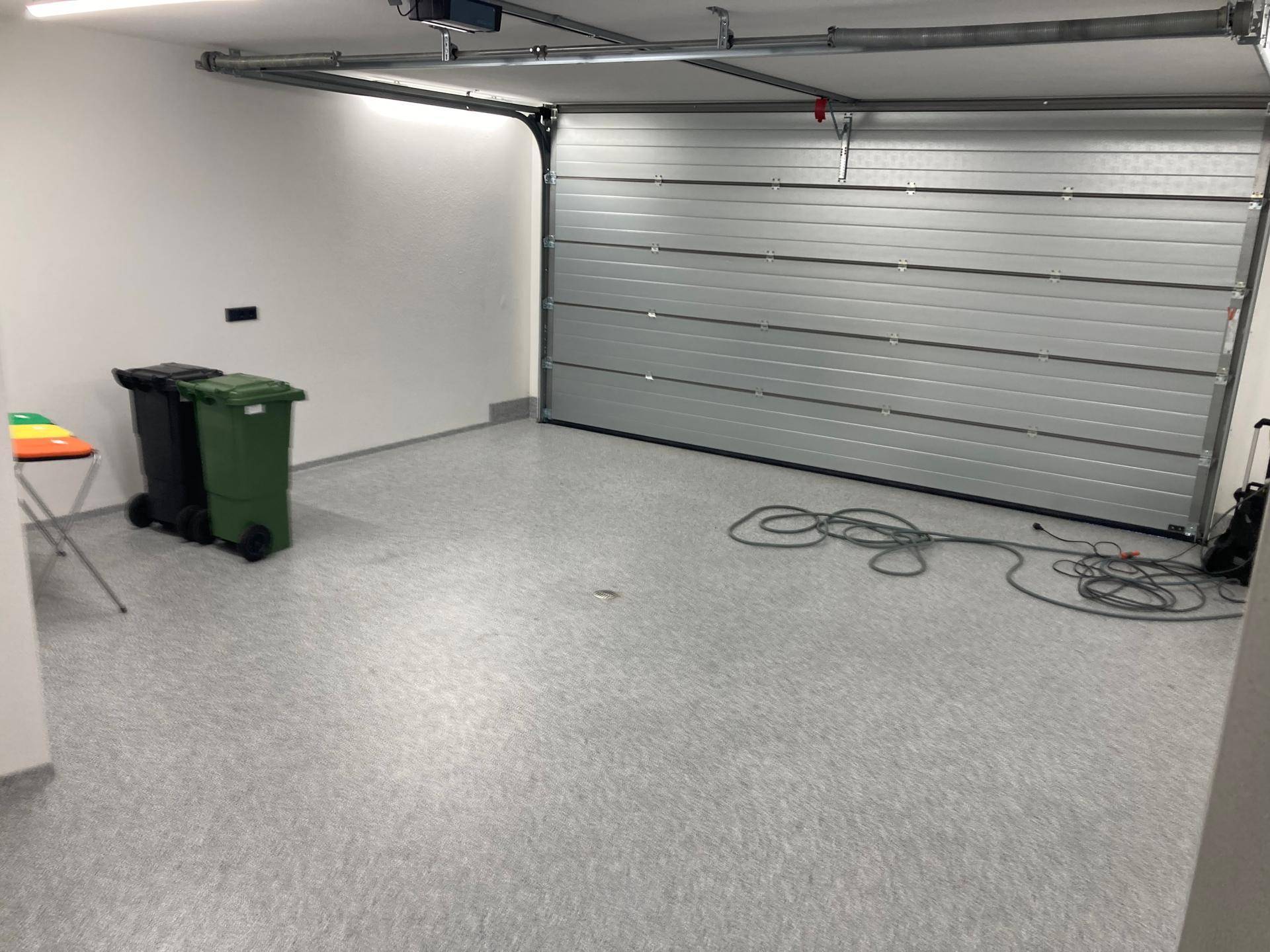 Große Garage mit automatischem Rolltor und viel Platz für Fahrzeuge und Lagerung.