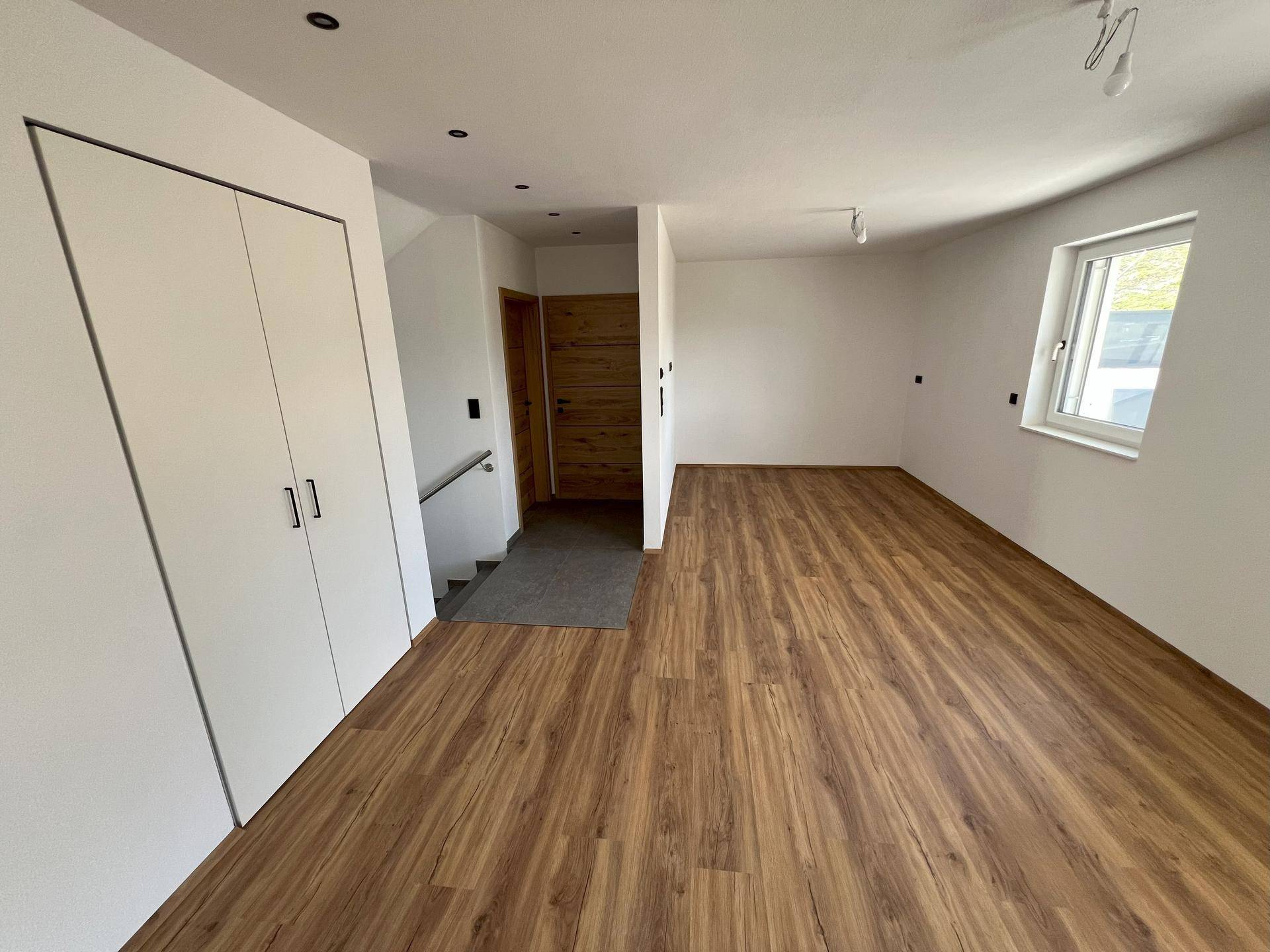 Geräumiger Flur mit Laminatboden, Einbauschränken und Holztür, hell und einladend.