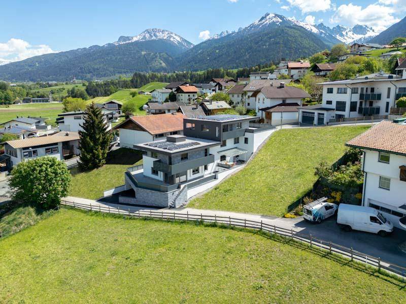 Weitläufige Ansicht des modernen Wohnhauses in einer Berglandschaft mit umliegenden Häusern.