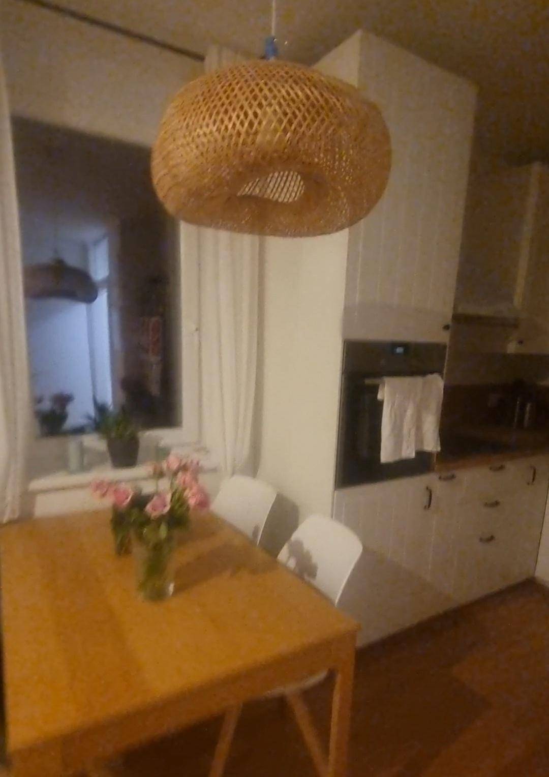 Essbereich in der Küche mit Holztisch, modernen Stühlen und einer auffälligen Korblampe.