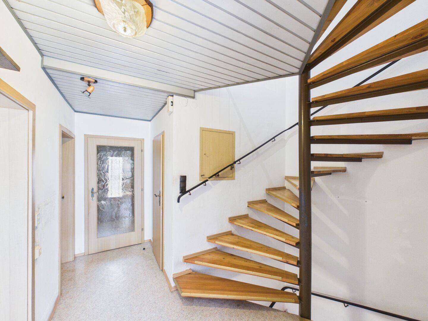 Heller Flur mit Holztreppe und Zugang zu verschiedenen Räumen im Haus.