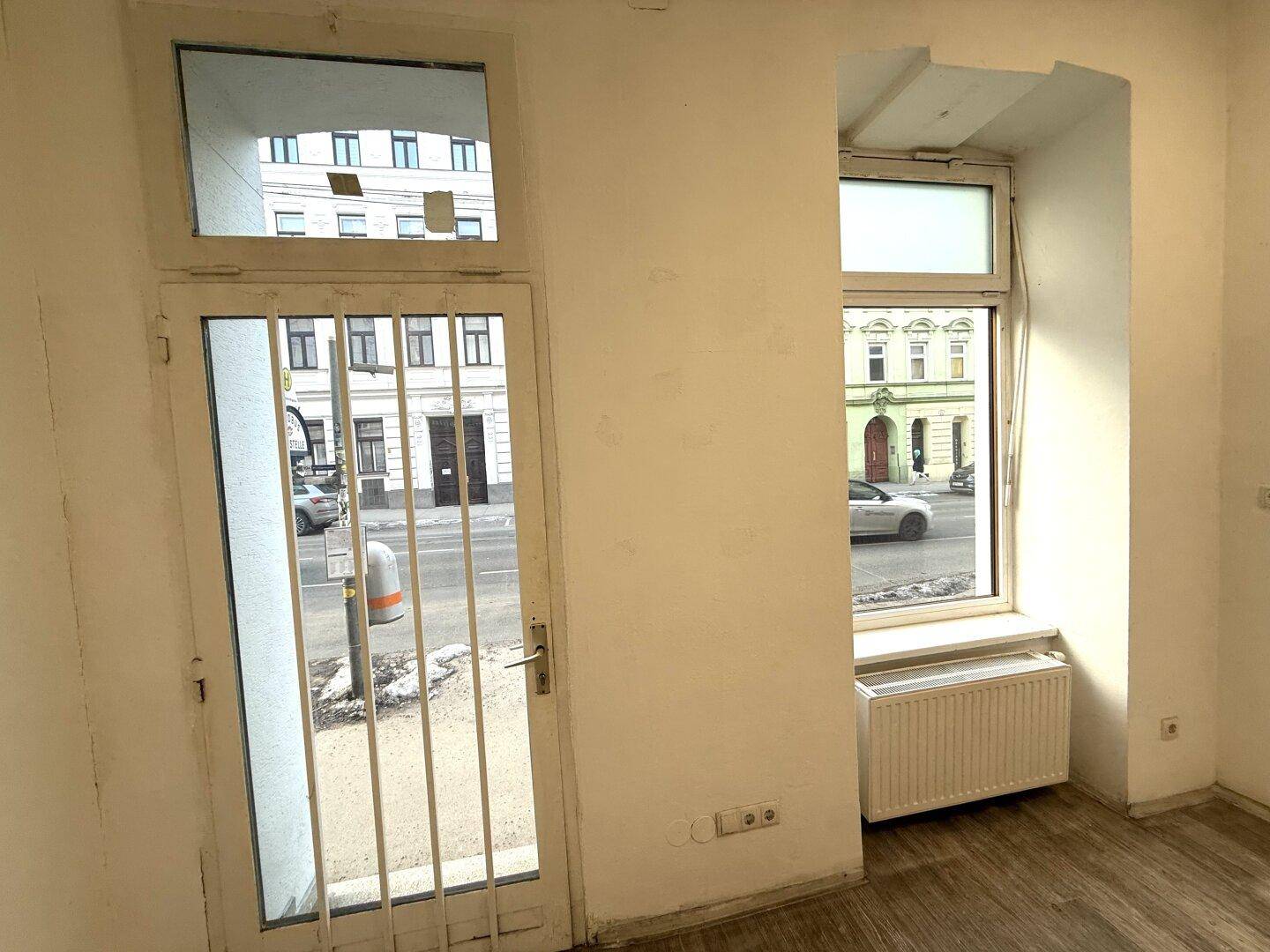 Glastür und großes Fenster eines Ladenraums mit Blick auf die belebte Straße.