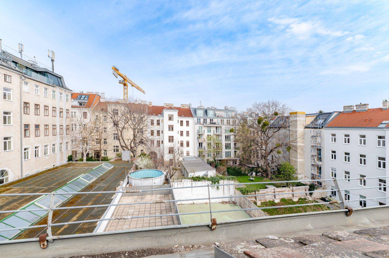 Blick über Dächer und Innenhöfe mit umliegenden Gebäuden und einem kleinen Aufstellpool.