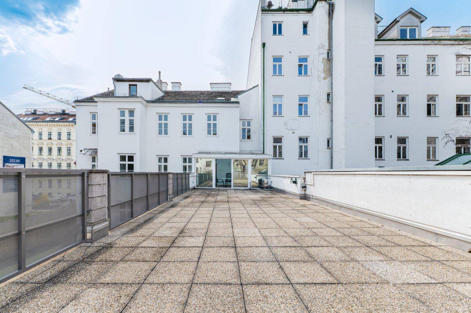 Große, geflieste Dachterrasse mit viel Platz und Blick auf die umliegende Stadtlandschaft.