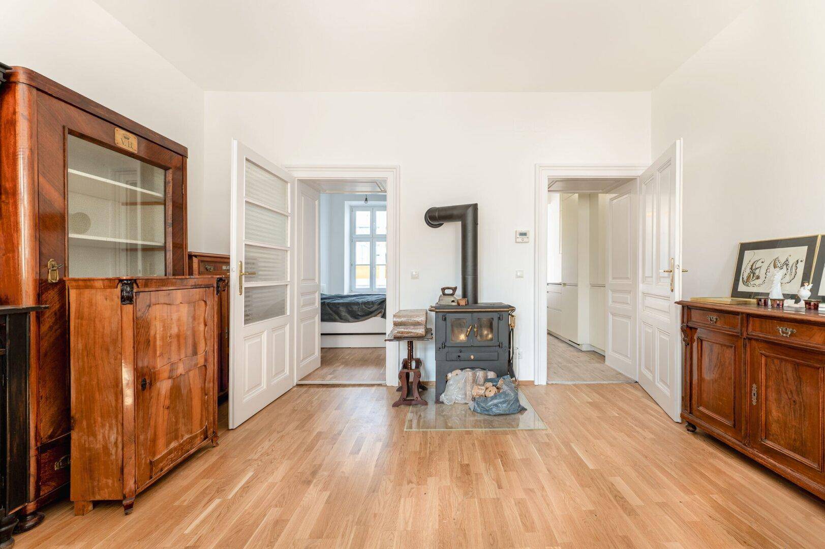 Gemütliches Wohnzimmer mit Holzboden, Kaminofen und antiken Holzmöbeln, strahlt Wärme aus.