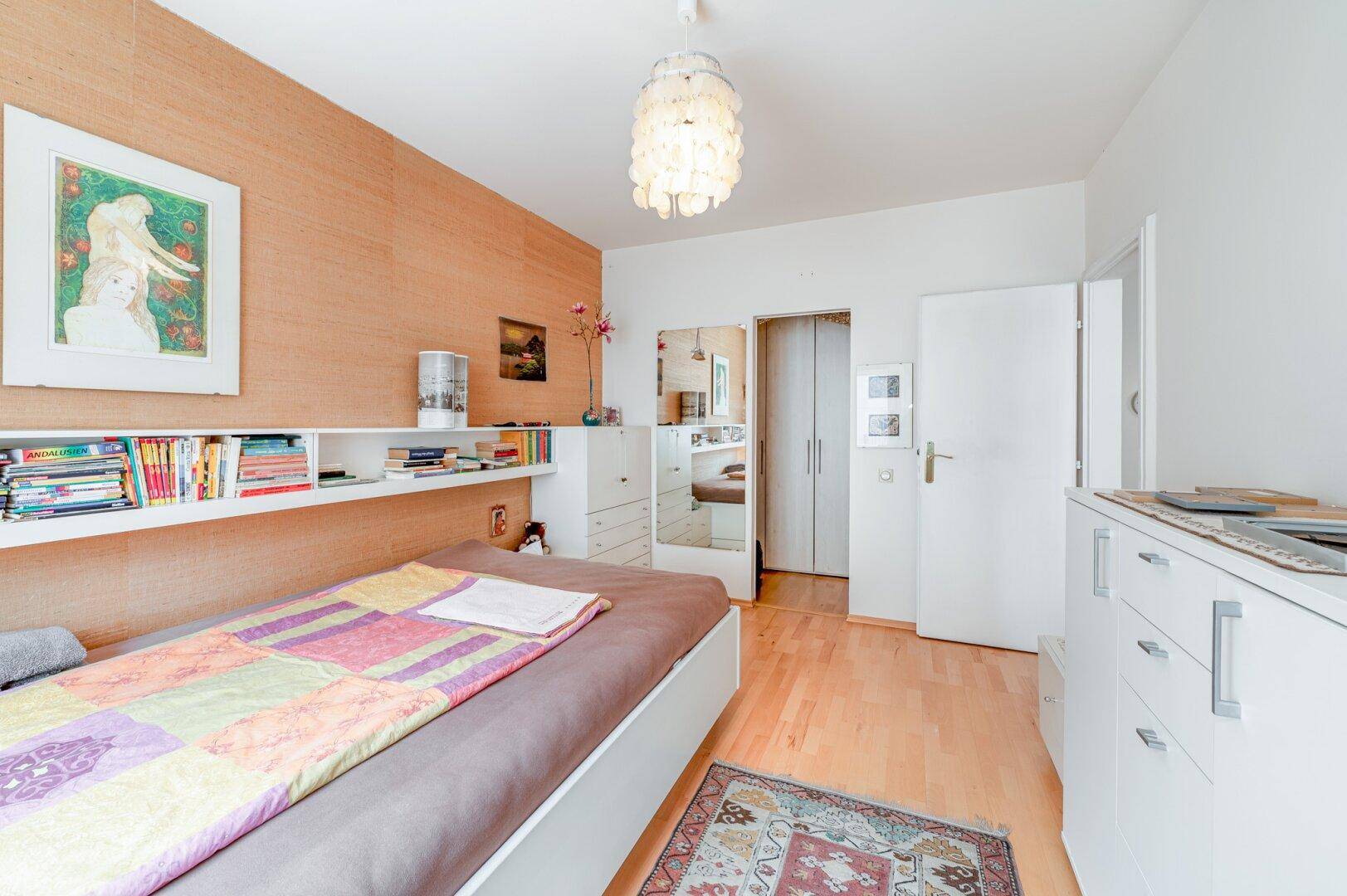 Gemütliches Schlafzimmer mit Parkettboden, einem Bett und einem großen Fenster, das viel Licht hereinlässt.