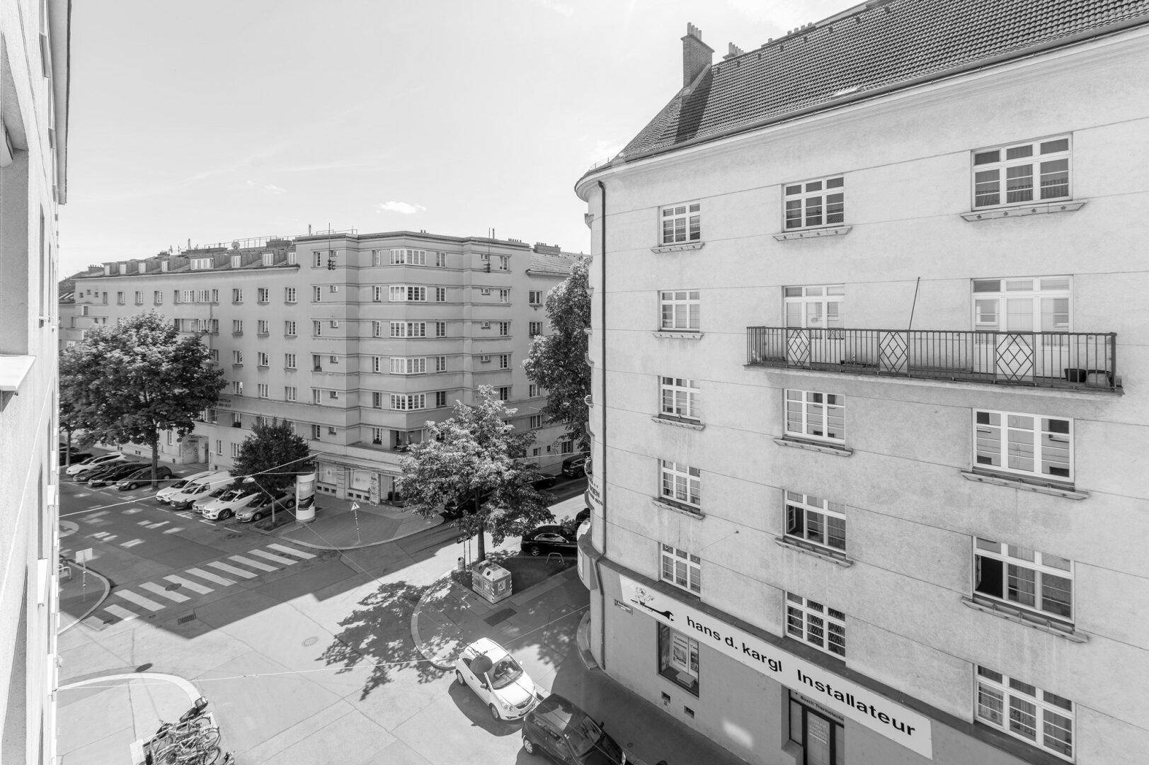 Schwarz-Weiß-Ansicht einer städtischen Umgebung mit Gebäuden, Bäumen und einer Kreuzung.