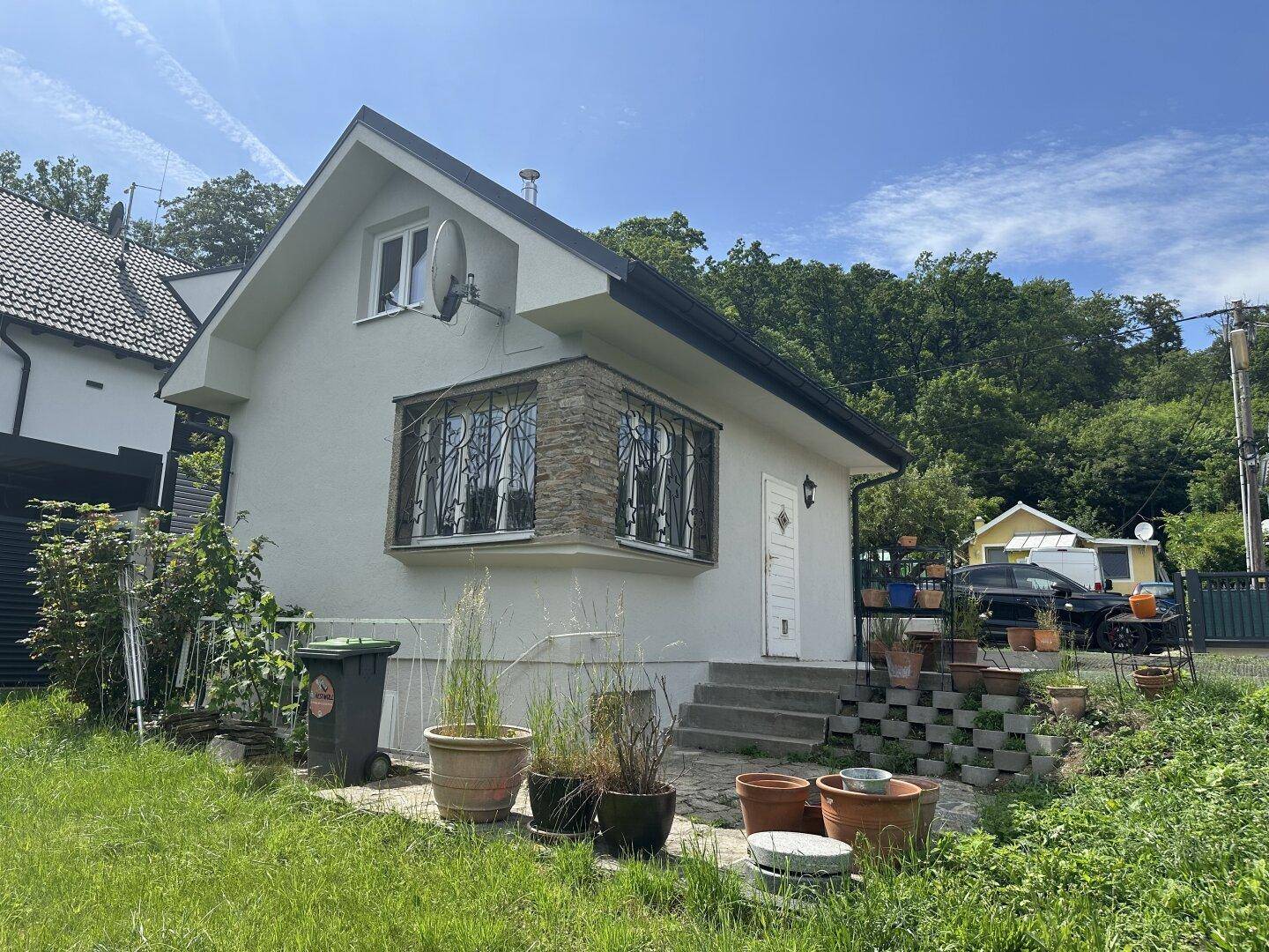Ansicht des Hauses mit Erkerfenster, Satellitenschüssel und umgebender Natur.