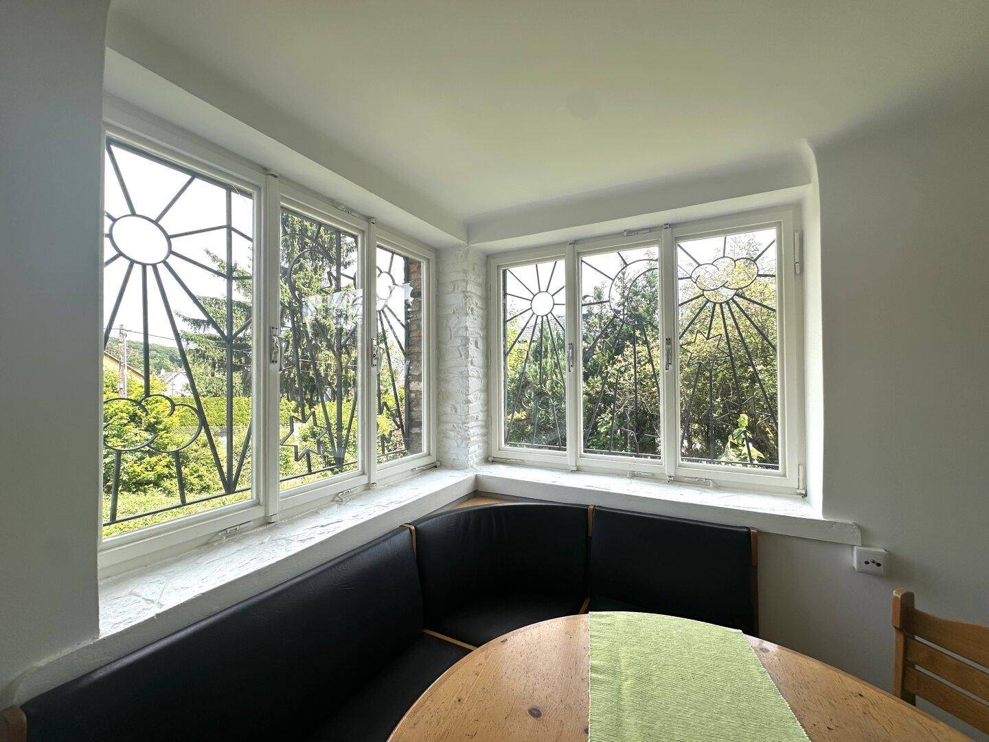 Detailansicht des Erkerfensters mit dekorativen Gittern und weitem Blick ins Grüne.